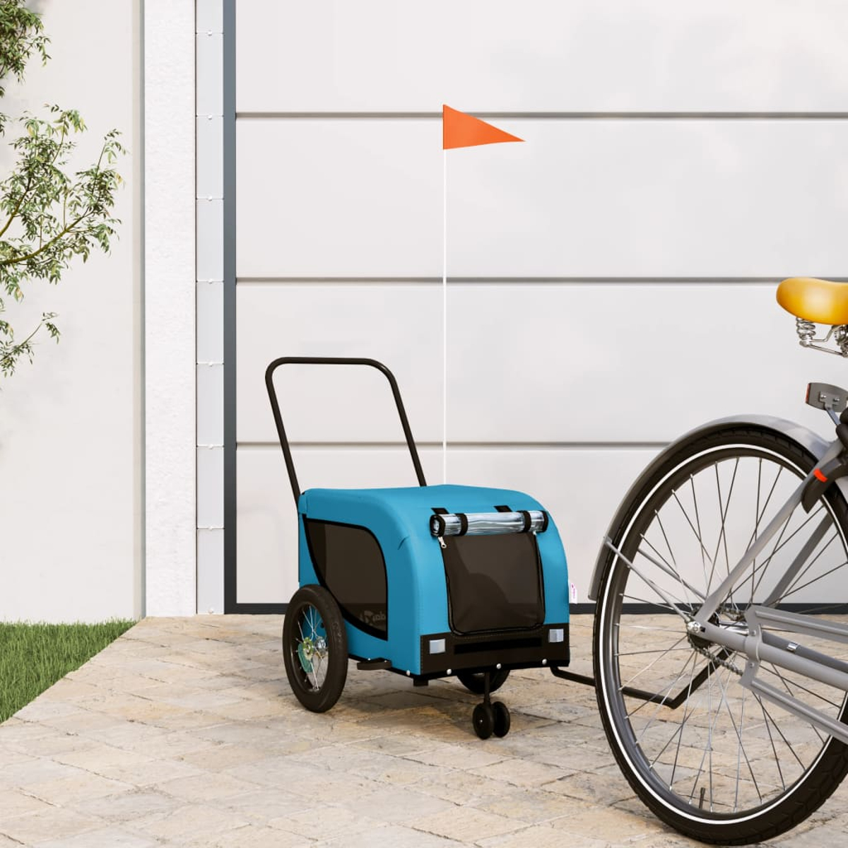 Ein blauer Fahrradanhänger mit einem orangen Wimpel steht neben einem Fahrrad.
