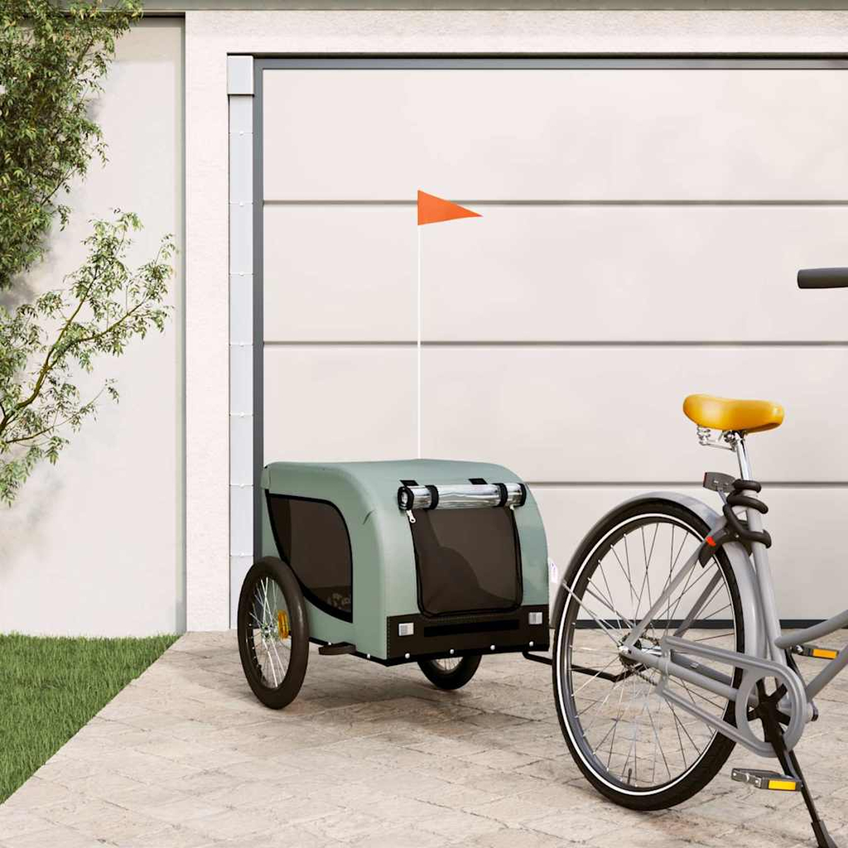 Ein graues Fahrrad mit Anhänger und orangener Flagge vor einem Garagentor.