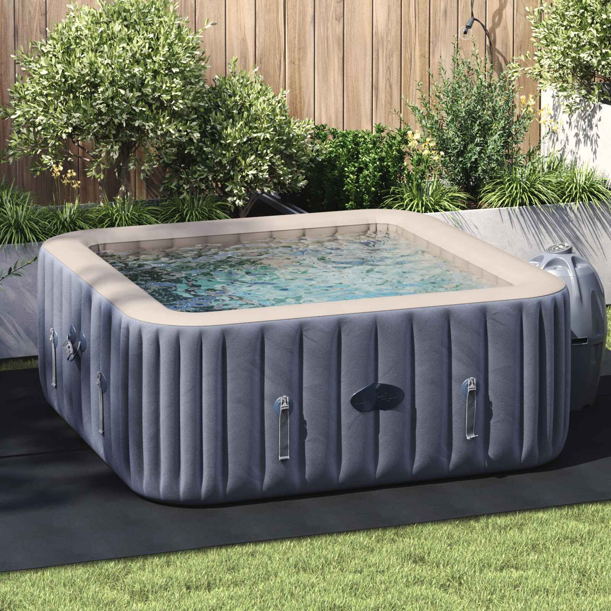 Aufblasbarer Whirlpool gefüllt mit Wasser in einem Garten mit Holzzaun und grünen Pflanzen.