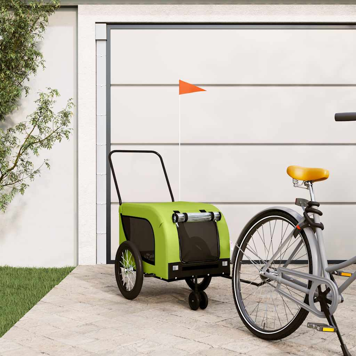 Ein grüner Fahrradanhänger mit orangenem Wimpel steht neben einem Fahrrad vor einer Garage.