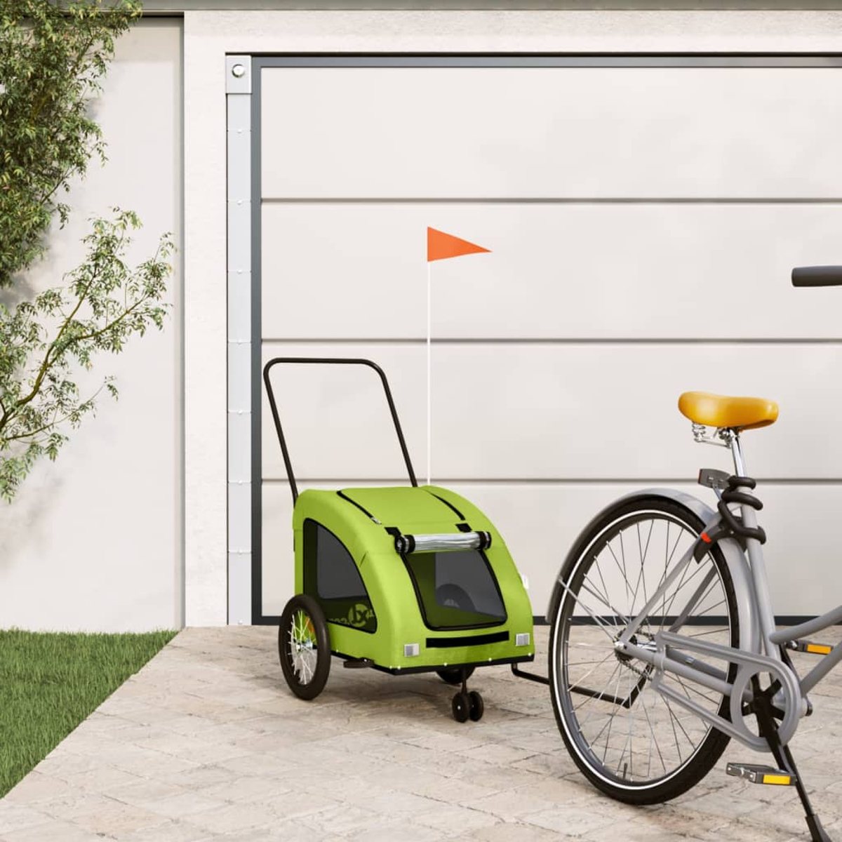 Ein grüner Fahrradanhänger mit orangenem Wimpel steht neben einem Fahrrad.