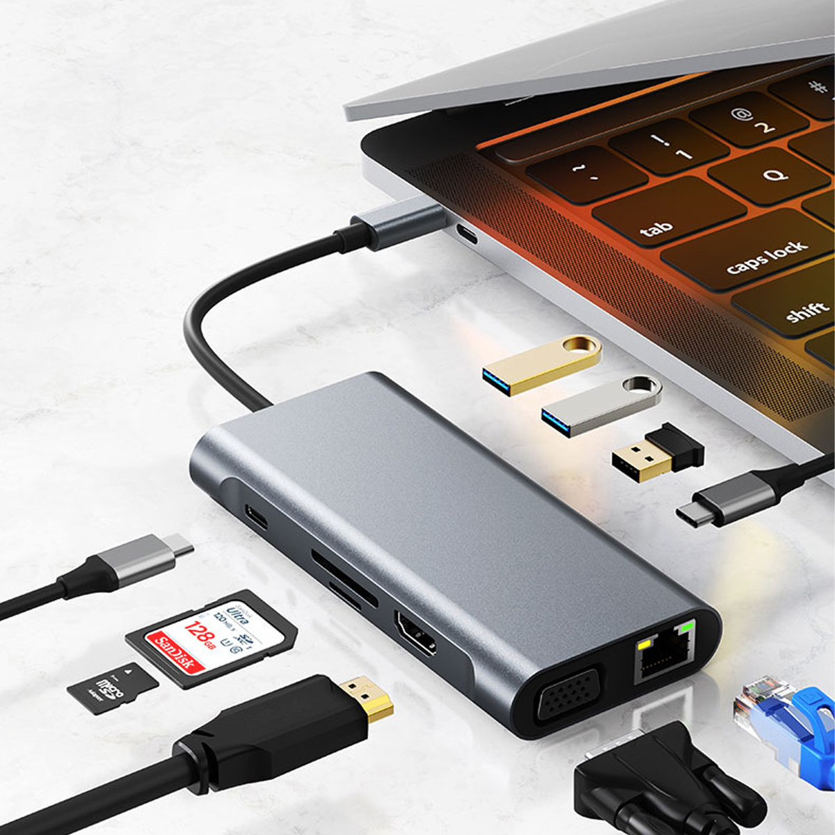 Ein grauer USB-C-Hub mit SD-Karten und Sticks neben einem Laptop.
