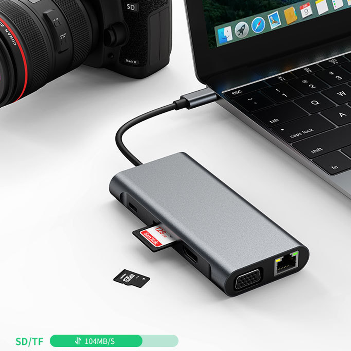 Grauer USB-C-Hub an Laptop angeschlossen, mit Kamera, SD-Karte und microSD-Karte daneben.