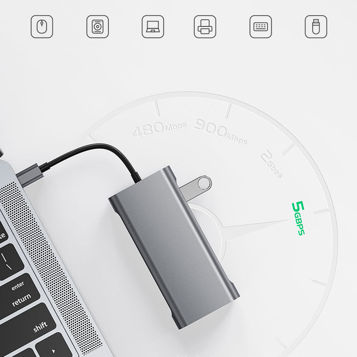 Grauer USB-C-Hub neben einem Laptop auf einem weißen Hintergrund mit Geschwindigkeitsangaben.