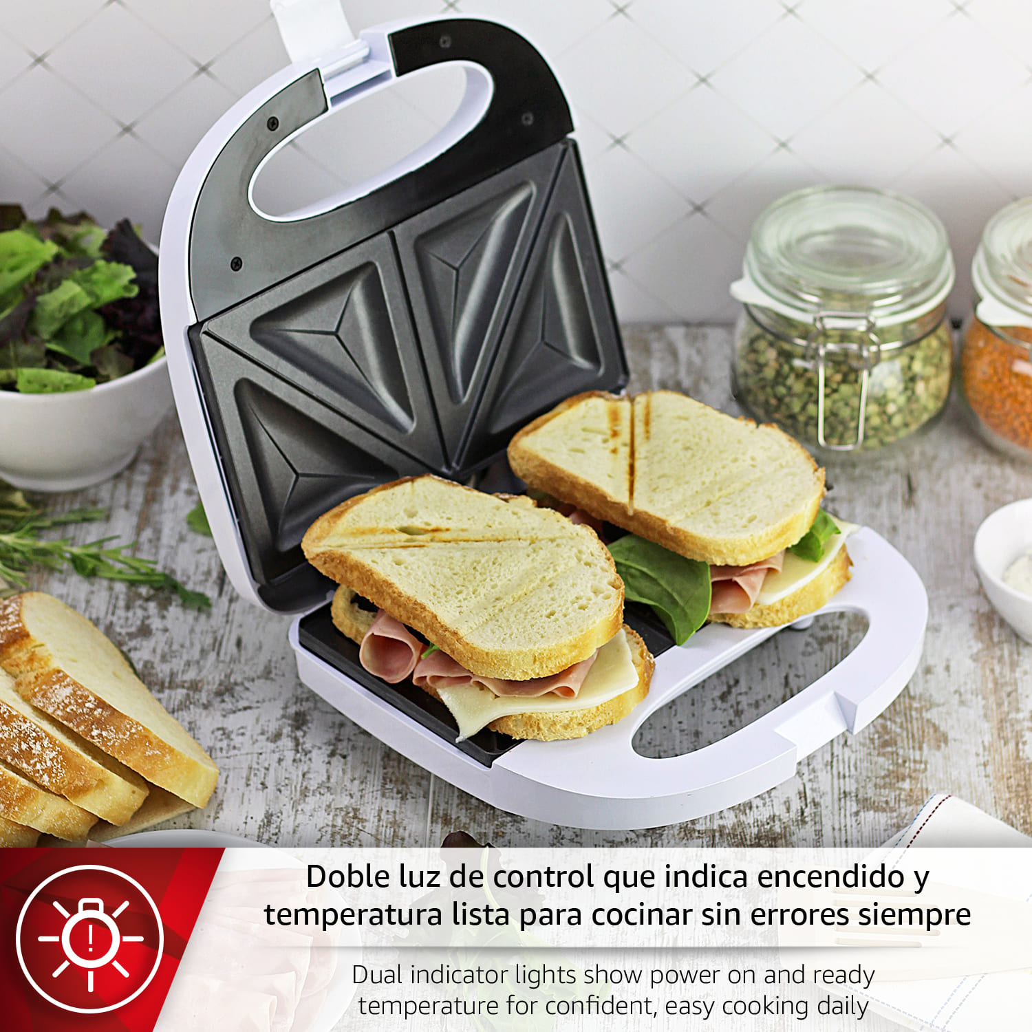 Sandwichera con dos sándwiches, pan y ensalada. Frascos de comida al fondo.