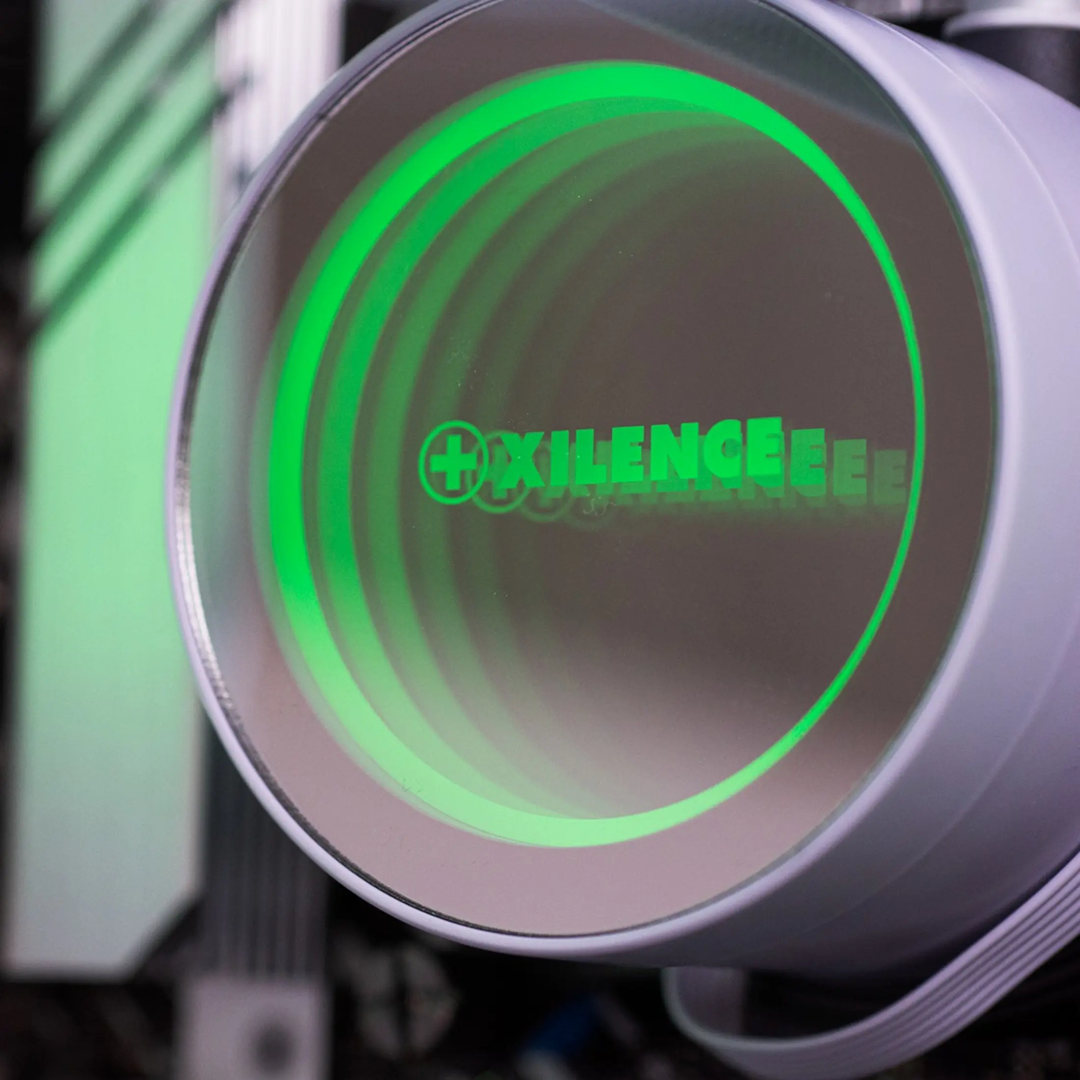 Een witte ventilator met groene verlichting en het "+XILENCE" logo.