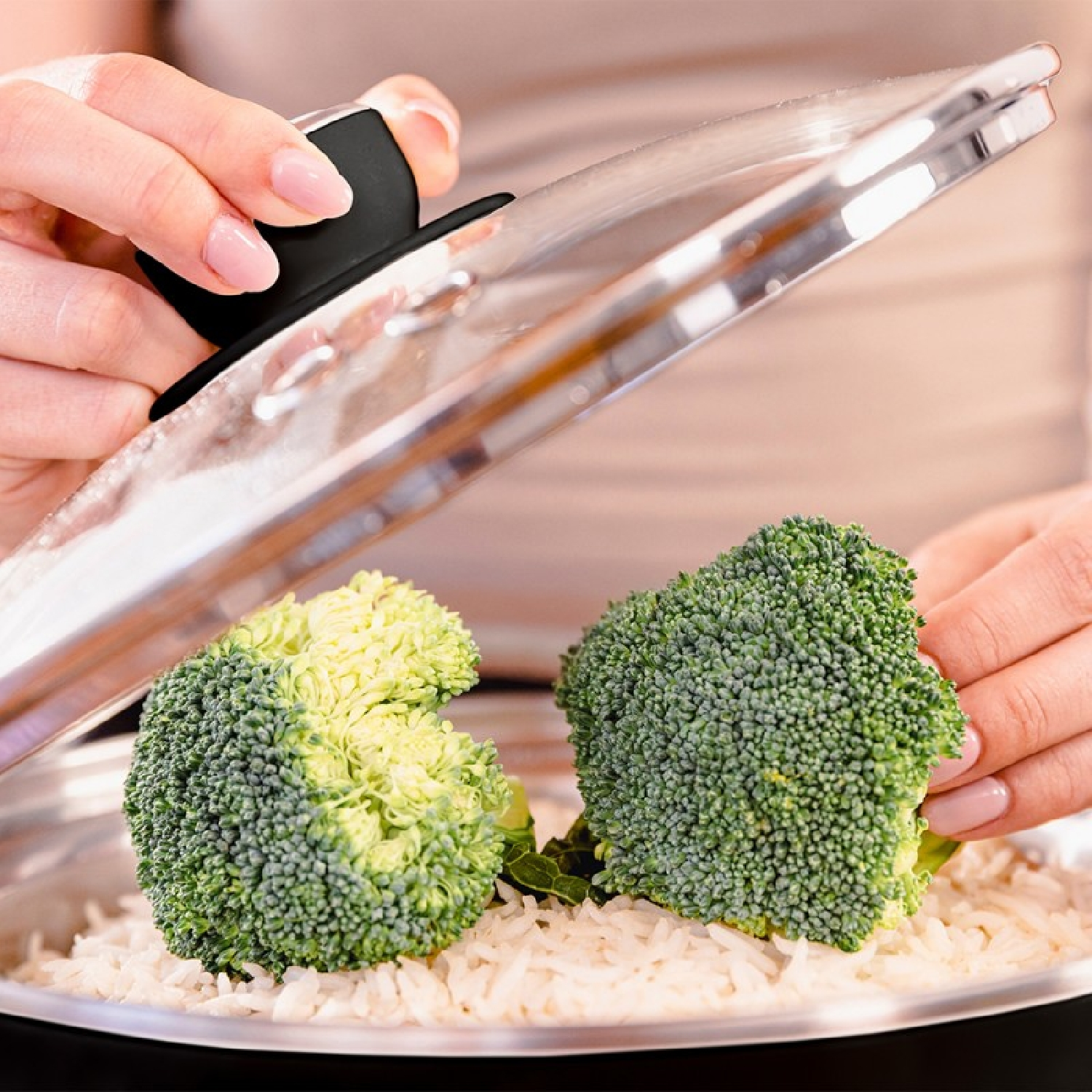 Cime di broccoli su riso, sollevate da una mano con pinze.