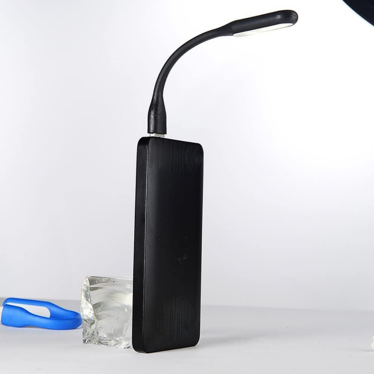 Un power bank nero con lampada USB flessibile, blocco di ghiaccio e oggetto blu.