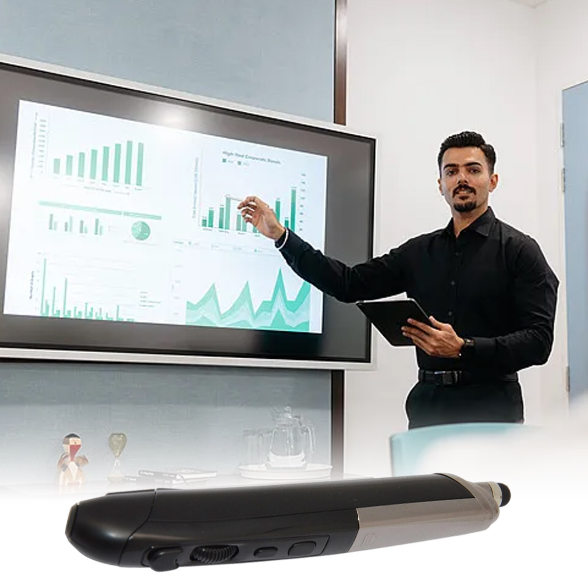 Uomo in camicia nera presenta grafici su schermo, tenendo un tablet.