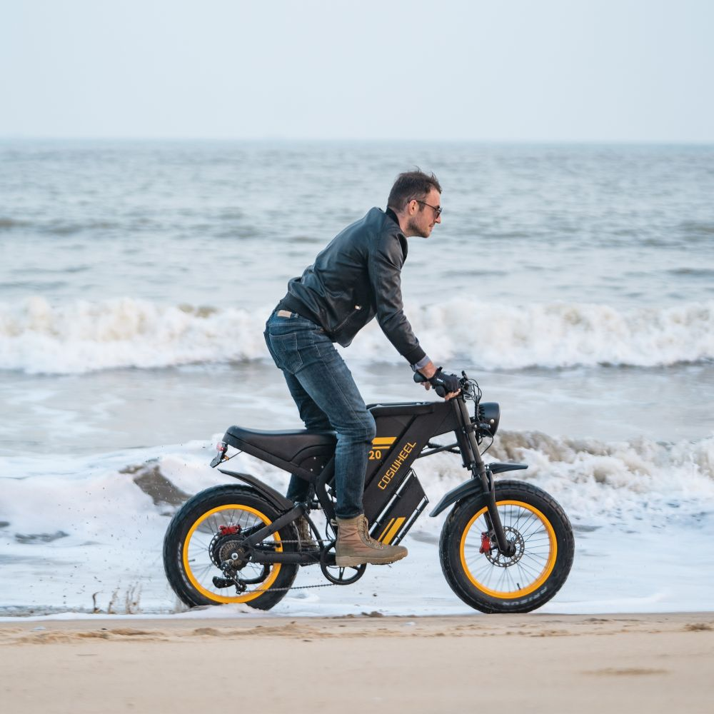 Hombre monta una bici eléctrica en la playa con olas.