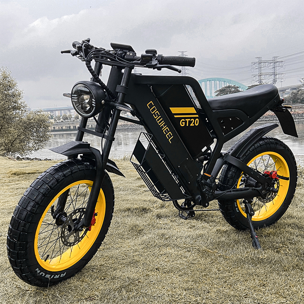 Una bici elettrica nera con cerchi gialli è sull'erba, con fiume e ponte sullo sfondo.
