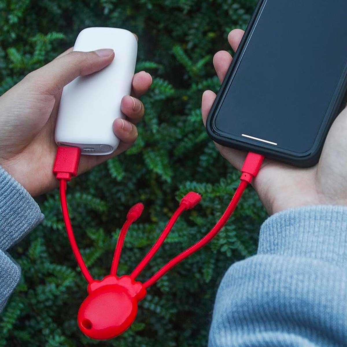 Une banque d'alimentation blanche et un smartphone sont connectés par des câbles rouges.