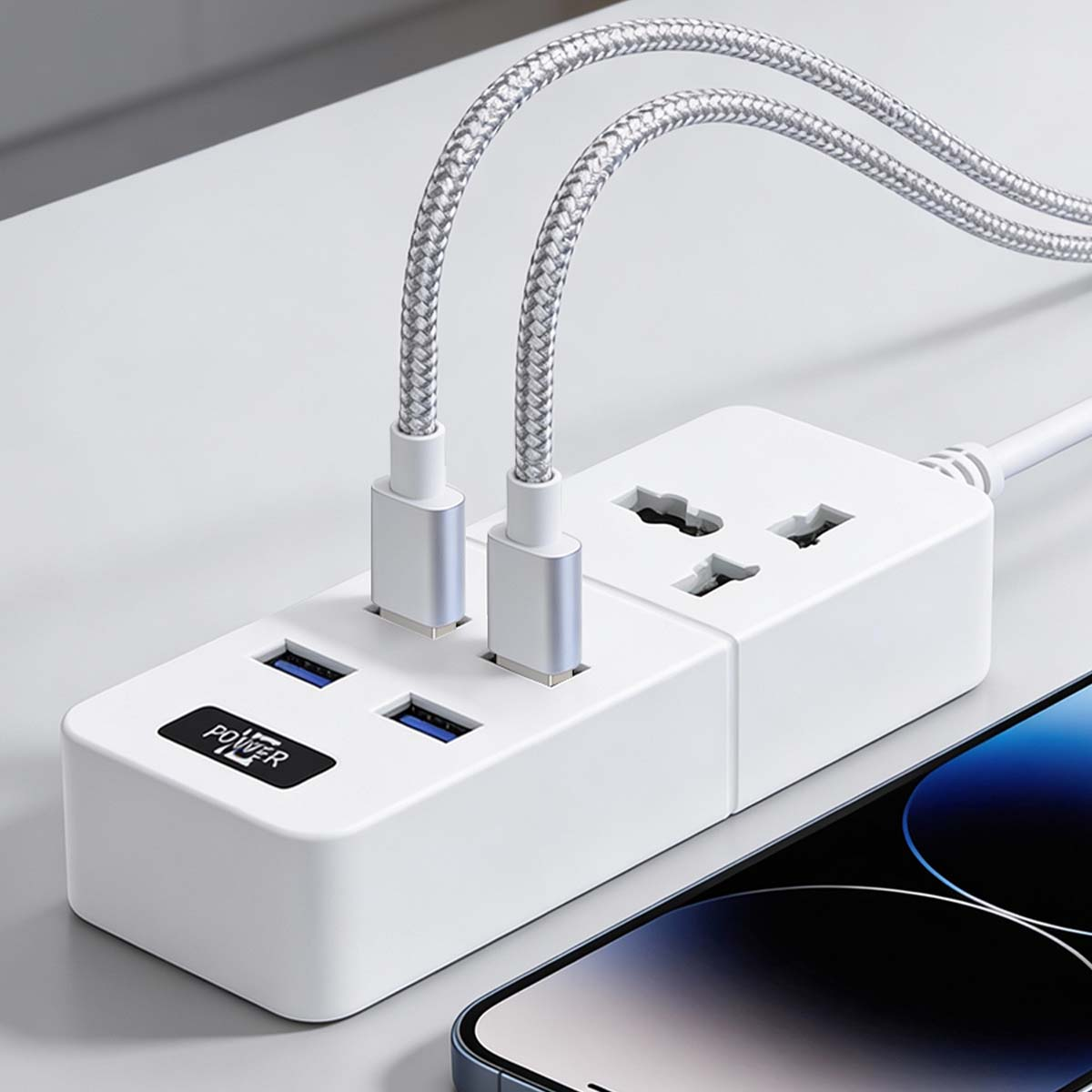 Weiße Steckdosenleiste mit USB-Anschlüssen und zwei eingesteckten Ladekabeln.