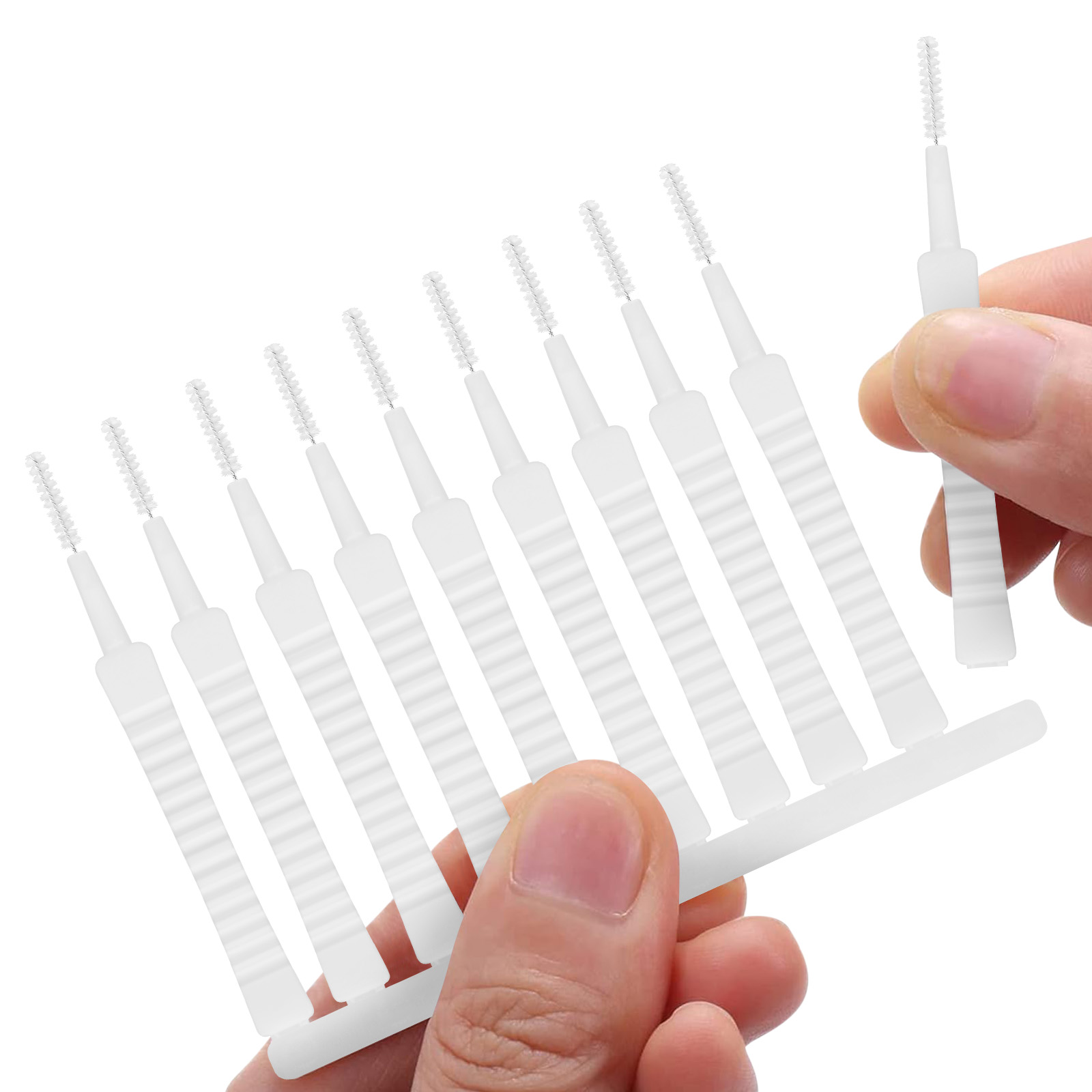 Weiße Interdentalbürsten in einer Reihe, eine Hand hält sie.