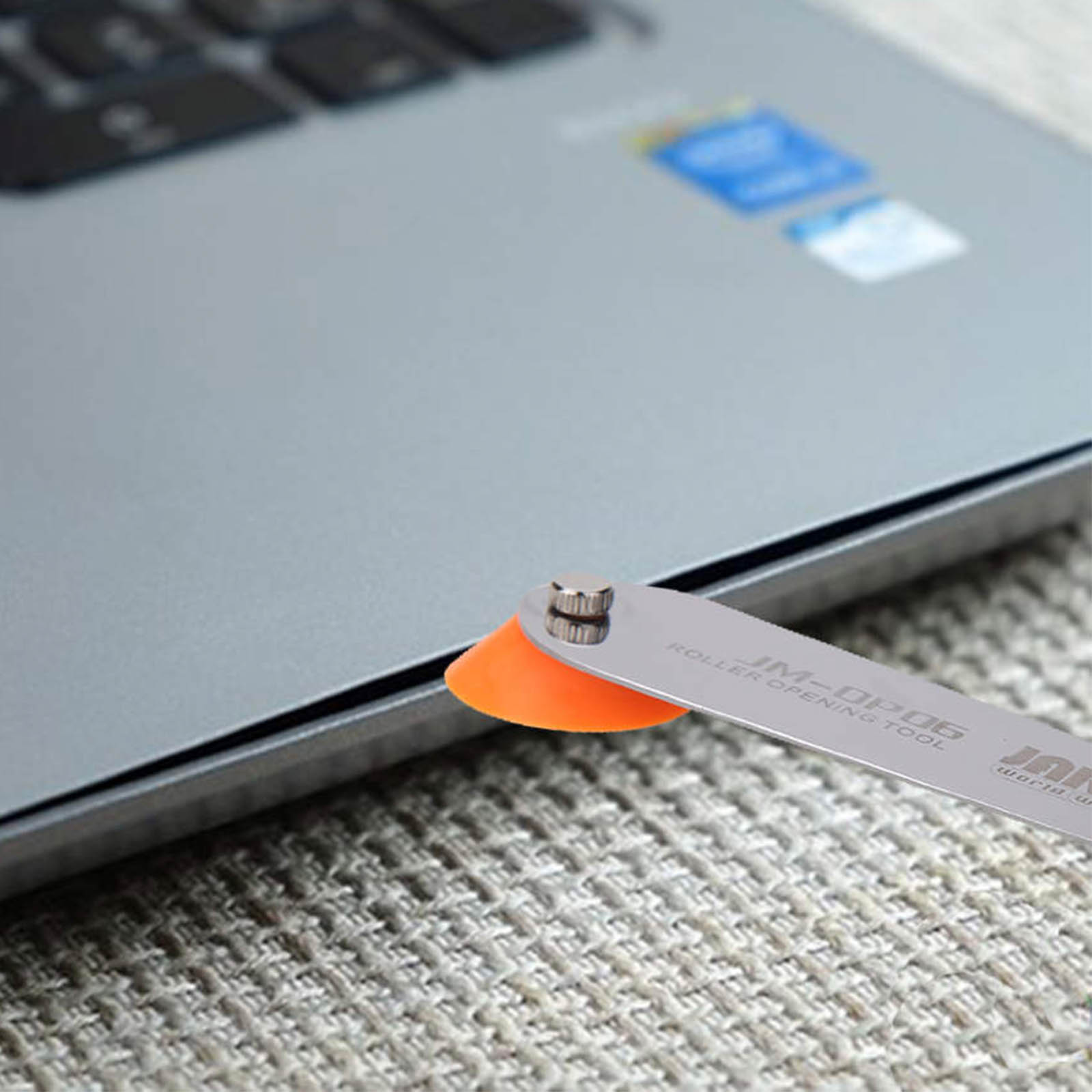 Uno strumento con ventosa apre un laptop su una superficie testurizzata.
