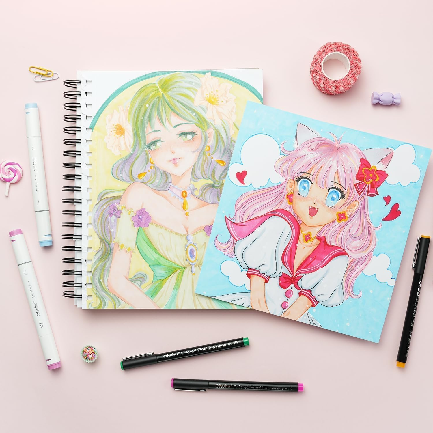 Zwei Anime-Mädchenzeichnungen, Marker und Schreibwaren auf rosa Hintergrund.