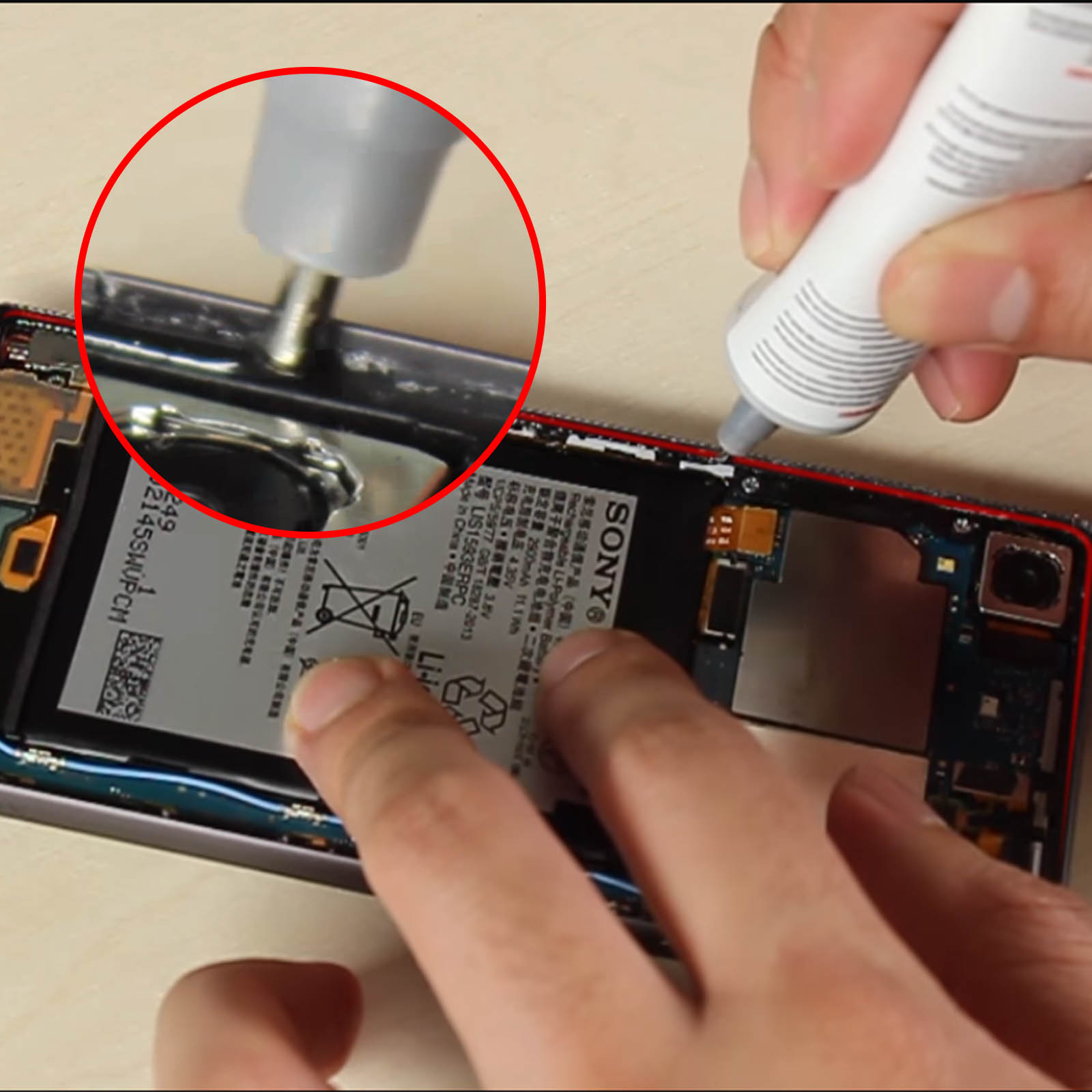 Mani che applicano colla all'interno di uno smartphone.