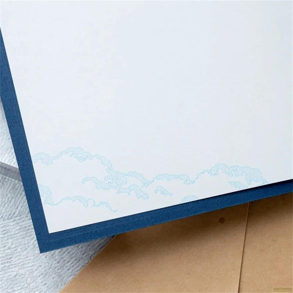 Blauer Rand mit Wolkenmuster auf weißem Papier, über braunem Umschlag.