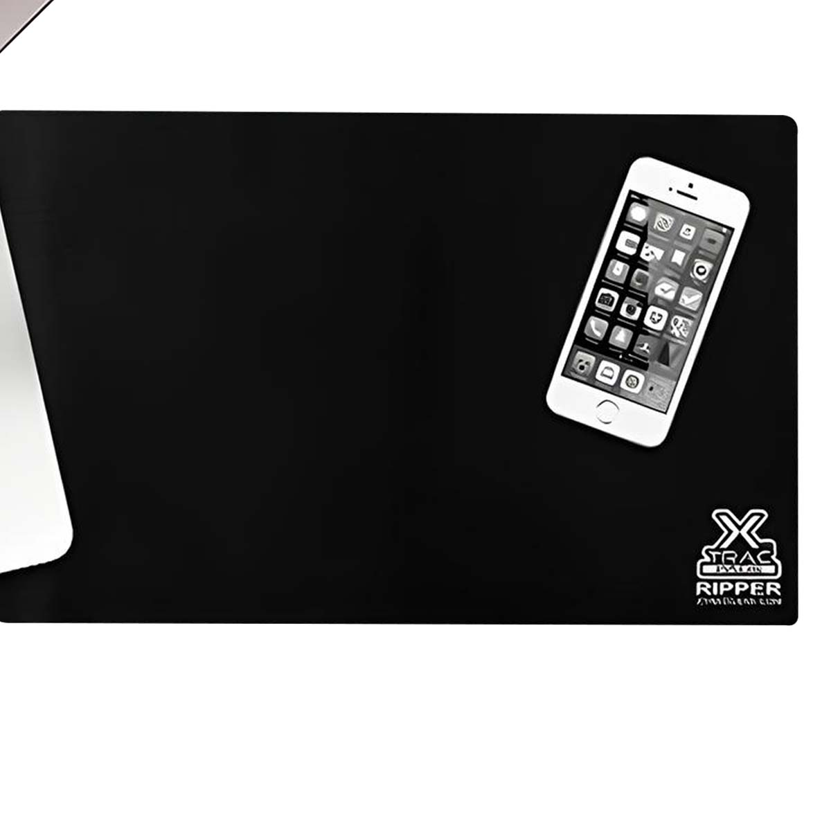 Uno smartphone bianco poggia su un tappetino nero accanto a un laptop.
