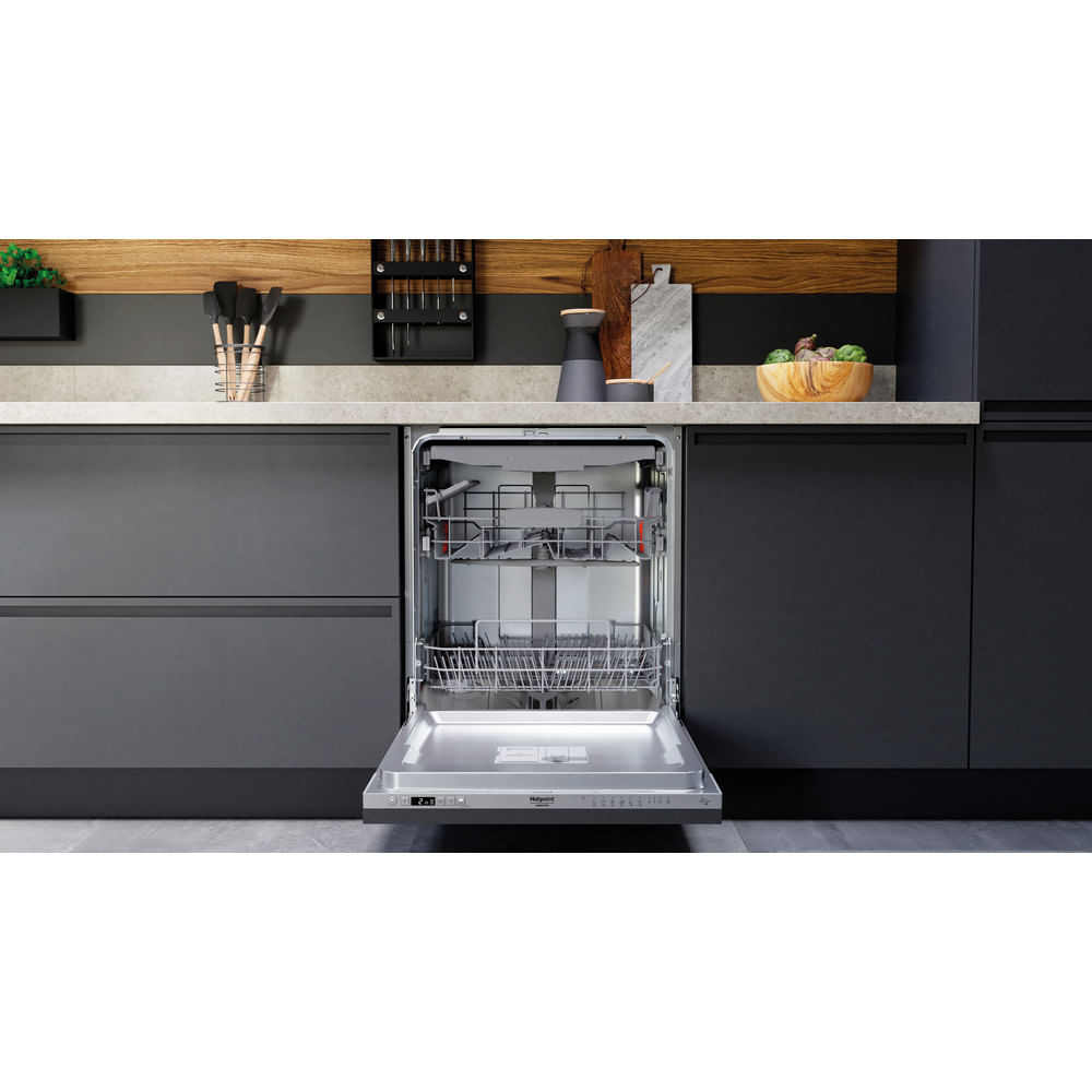 Una lavastoviglie aperta in una cucina moderna con mobili scuri.