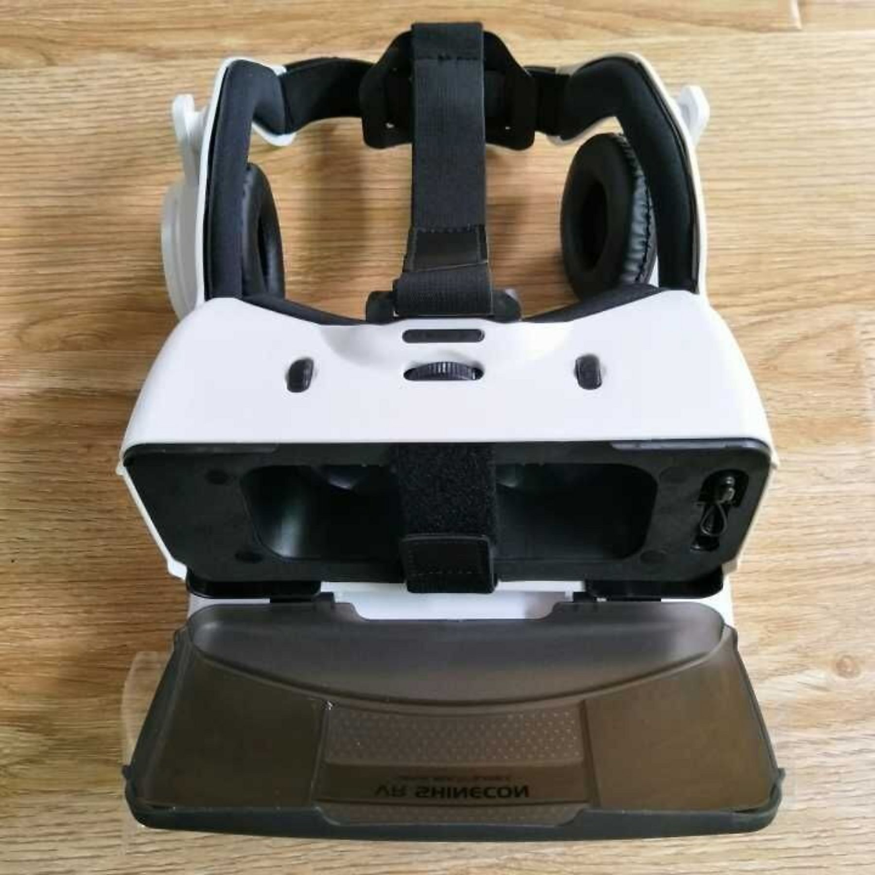 Weiße VR-Brille mit Kopfhörern auf Holzhintergrund.