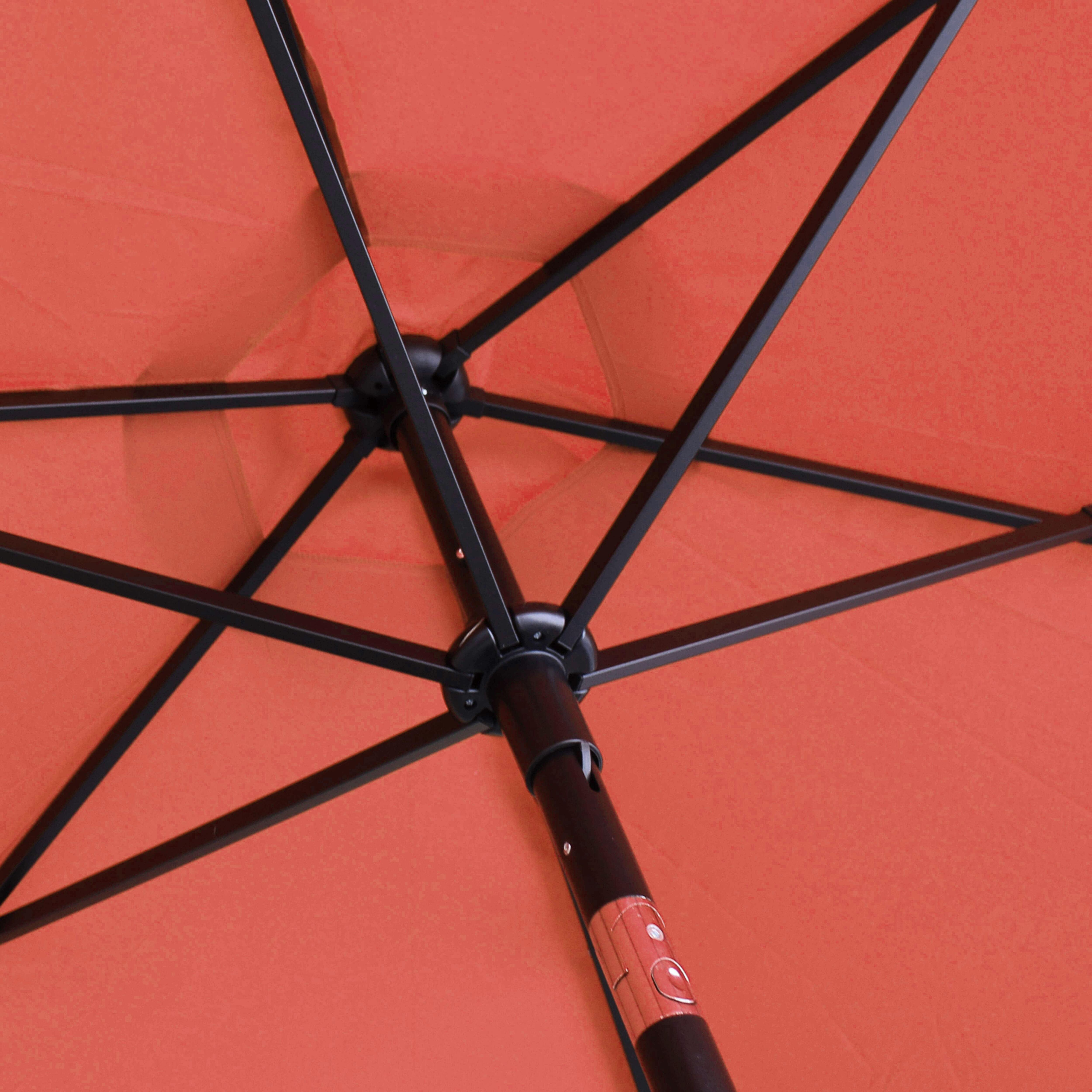 Innenseite eines orangefarbenen Sonnenschirms mit schwarzem Metallgestell und zentraler Stange.