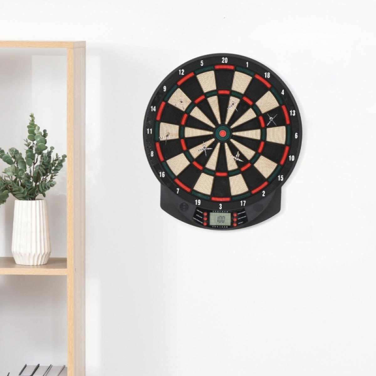Elektronische Dartscheibe an einer Wand mit einem Regal und Pflanze daneben.