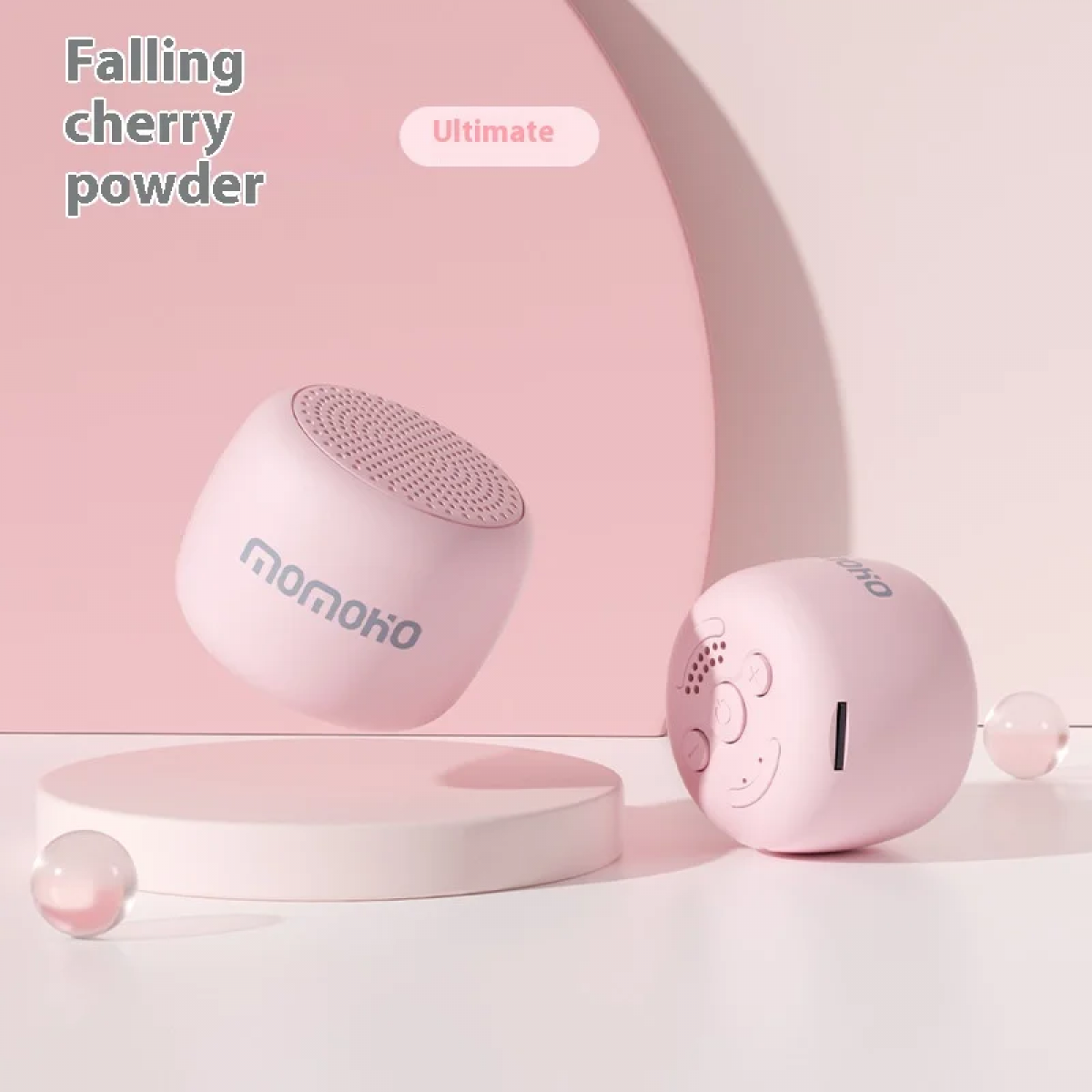 Zwei rosa Momoko-Lautsprecher auf einem rosa Podest vor einem sanften Hintergrund.