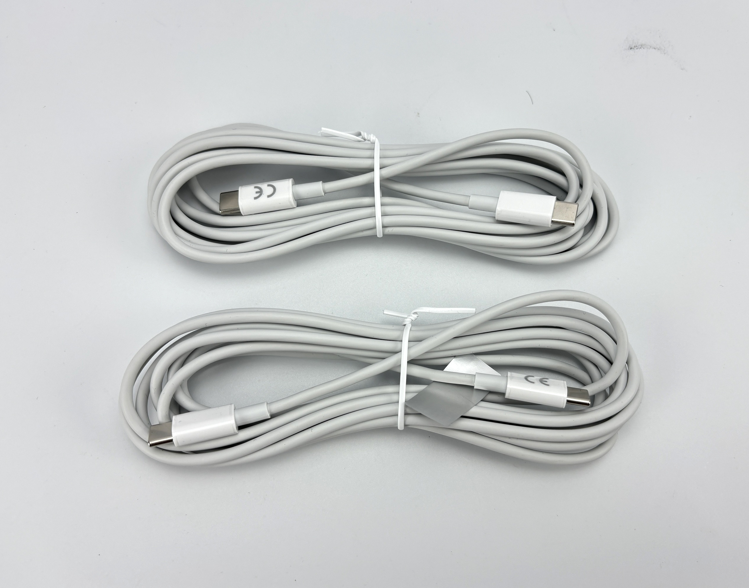 Twee witte USB-C kabels op een grijze achtergrond.