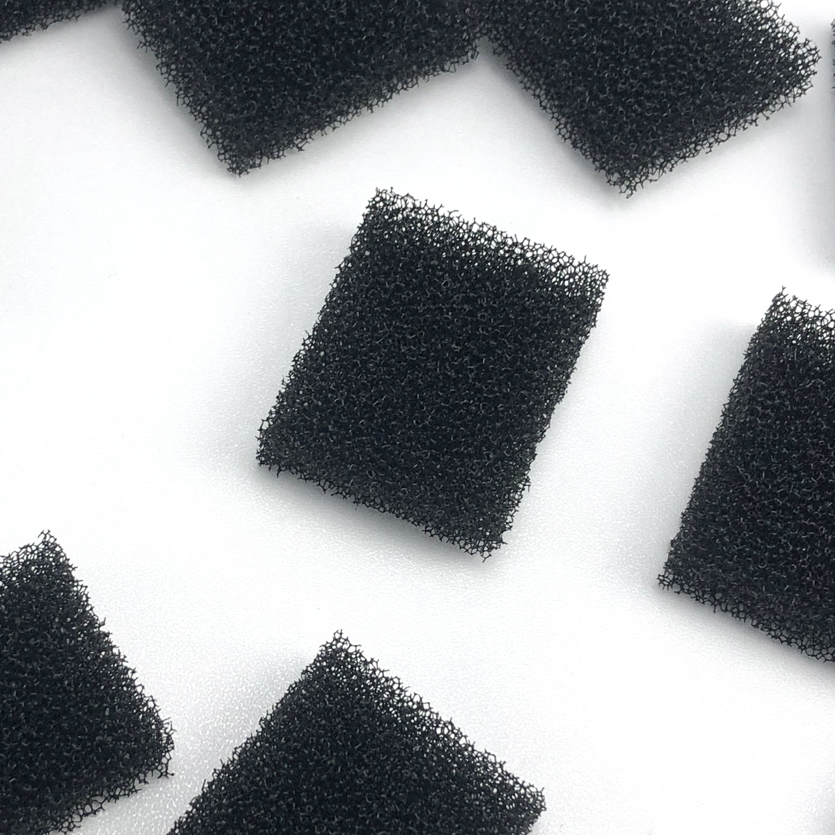 Mehrere schwarze Schaumstoffwürfel liegen auf weißem Hintergrund.