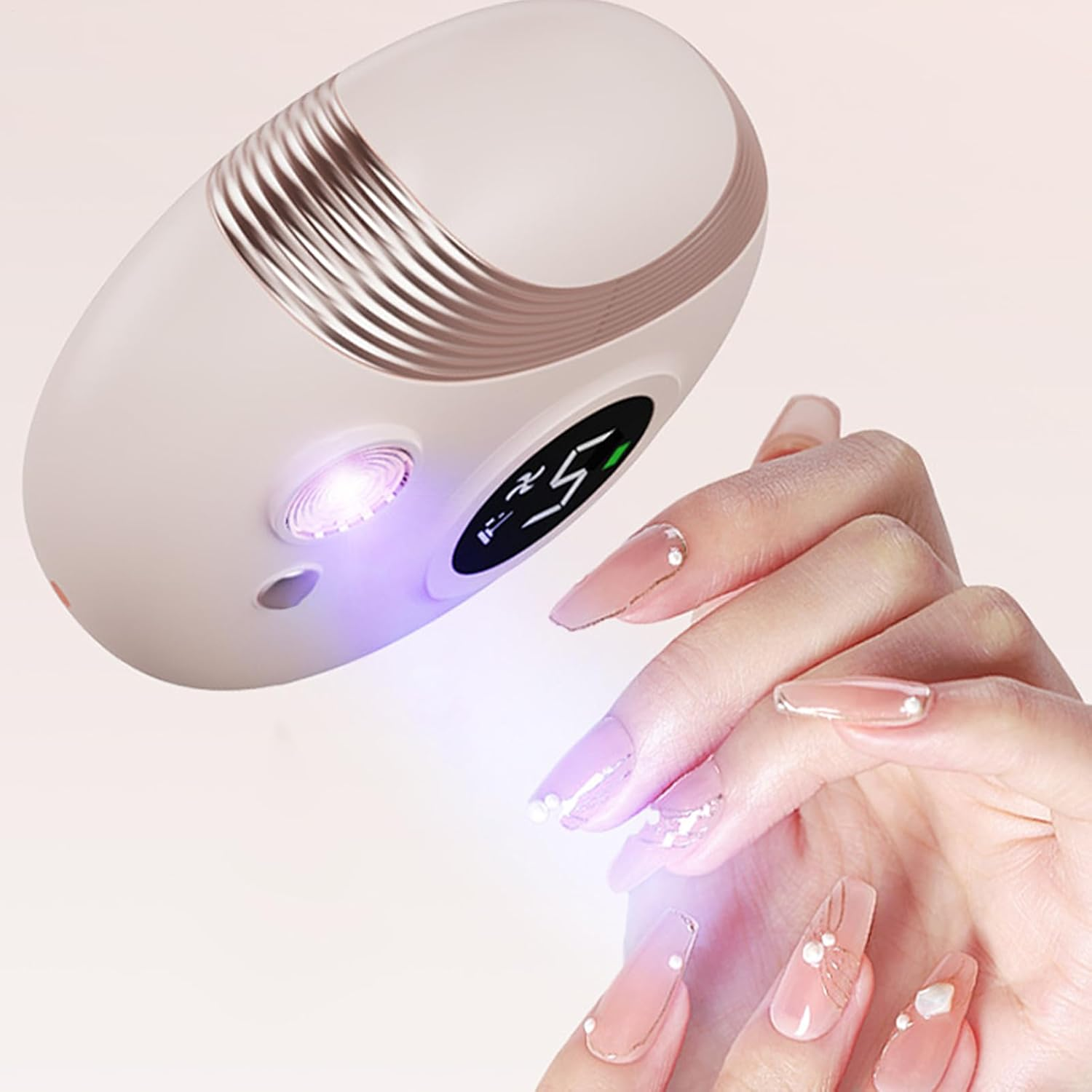 Eine Hand mit langen, verzierten Nägeln wird von einer UV-Lampe für Nägel beleuchtet.