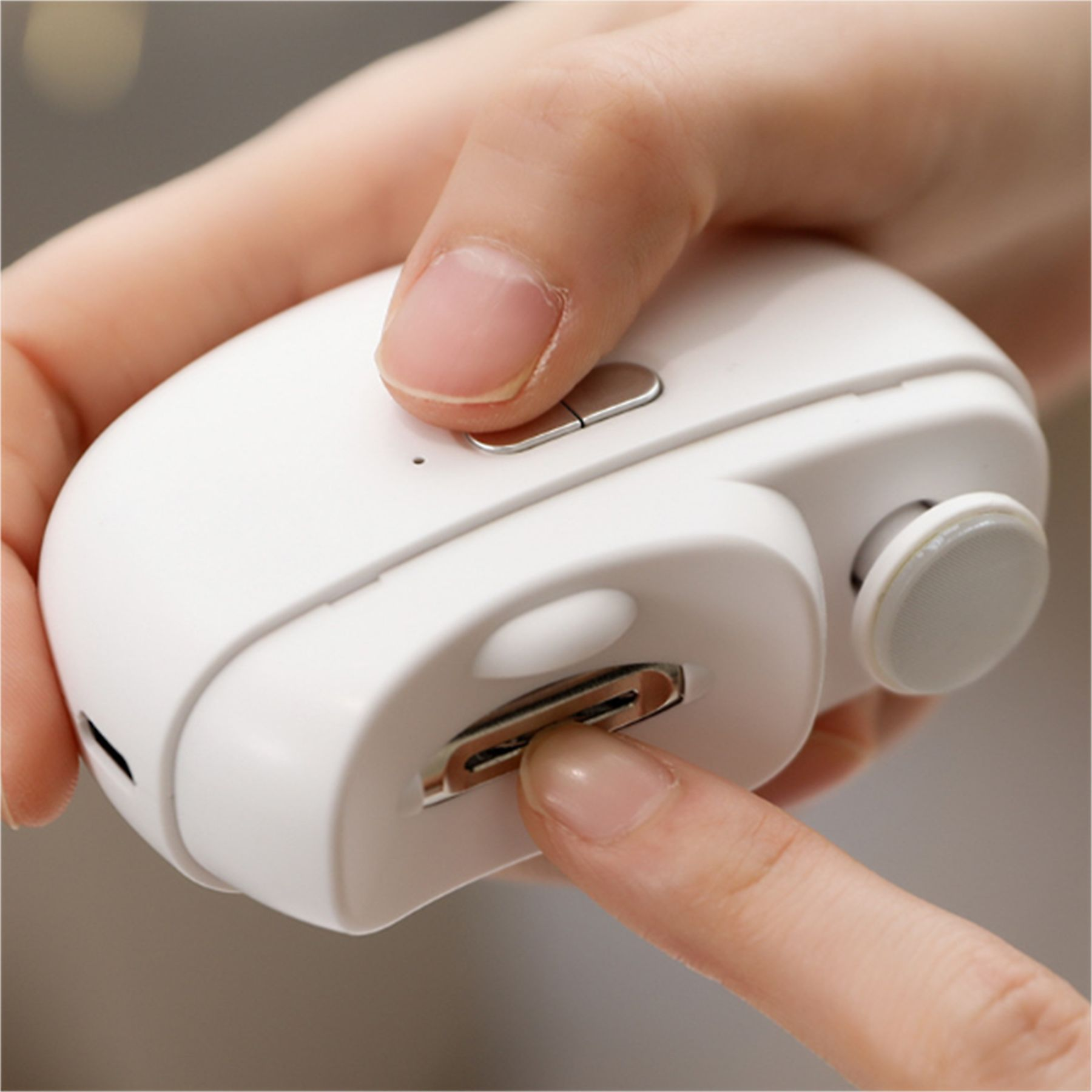 Eine weiße Maus mit einem USB-C-Anschluss, der von einem Finger eingeführt wird.
