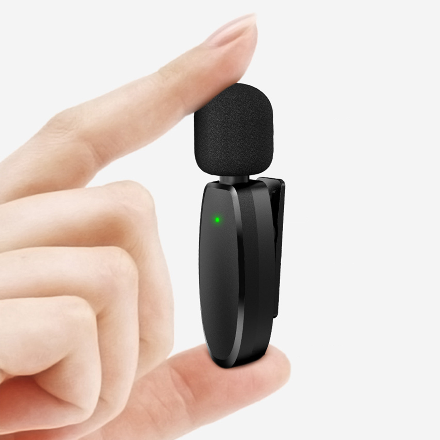Dłoń trzyma mały czarny mikrofon z zielonym światłem.