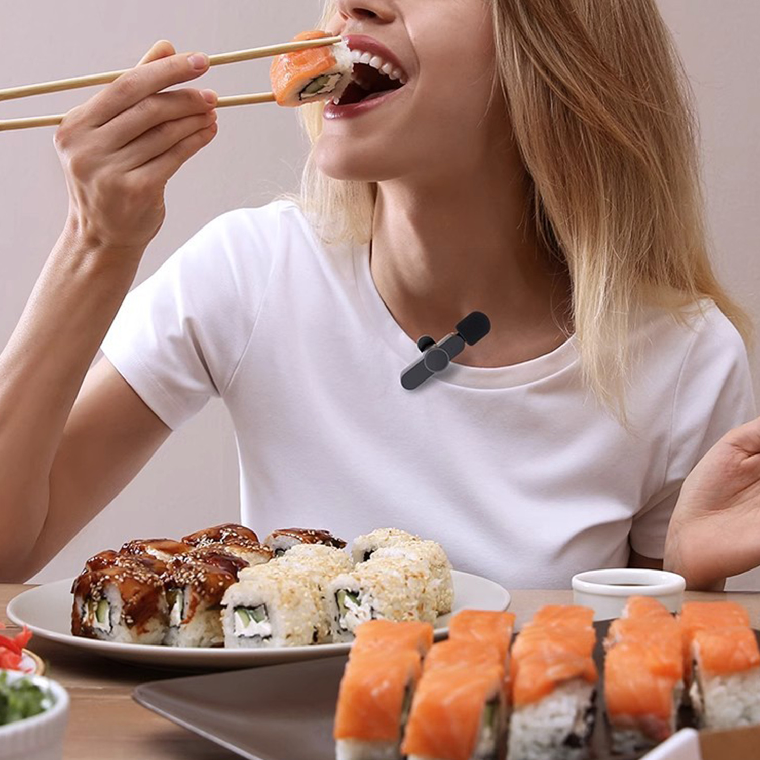 Kobieta je sushi pałeczkami. Do koszulki przypięty jest mikrofon.
