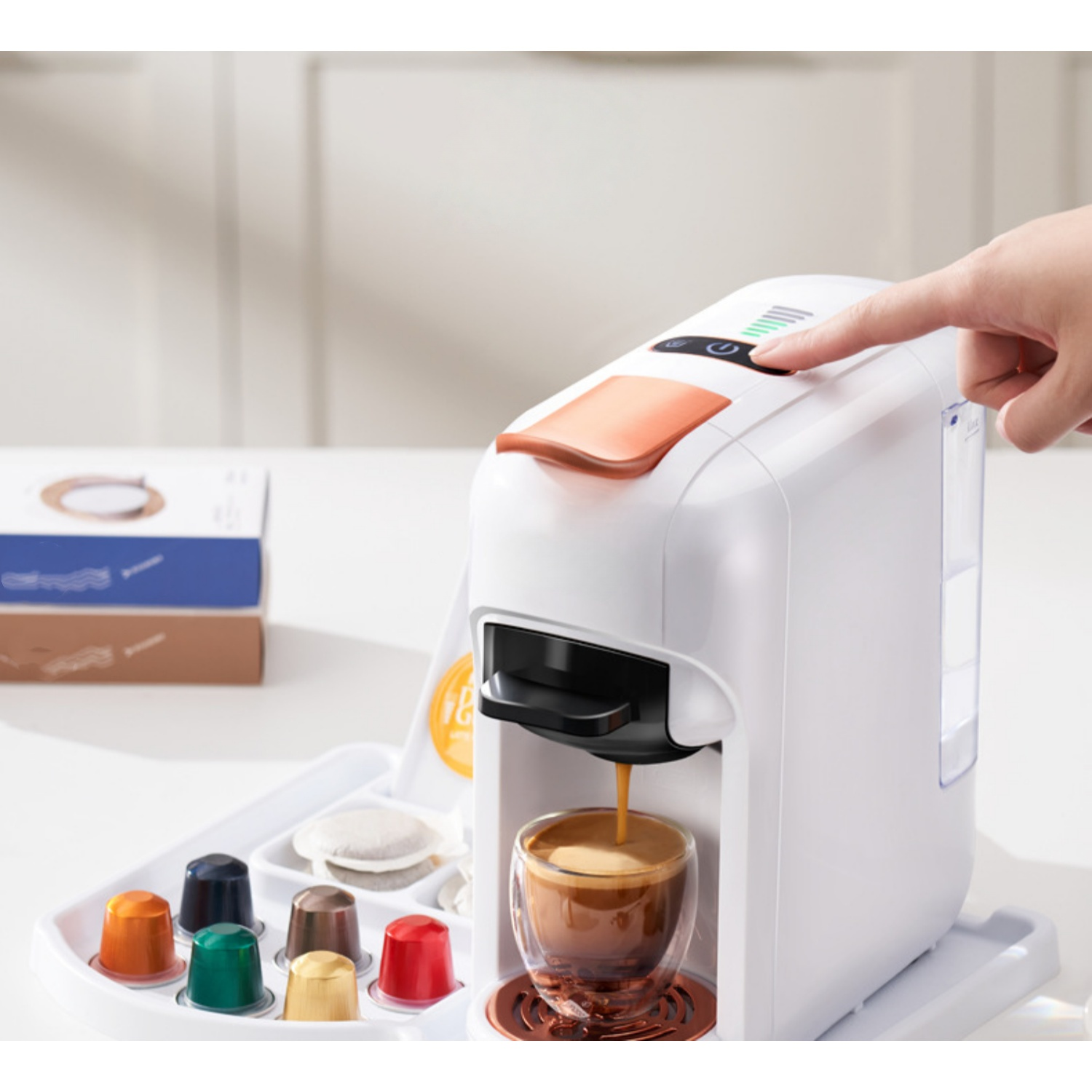 Eine weiße Kaffeemaschine bereitet Espresso in ein Glas zu. Kapseln liegen daneben.