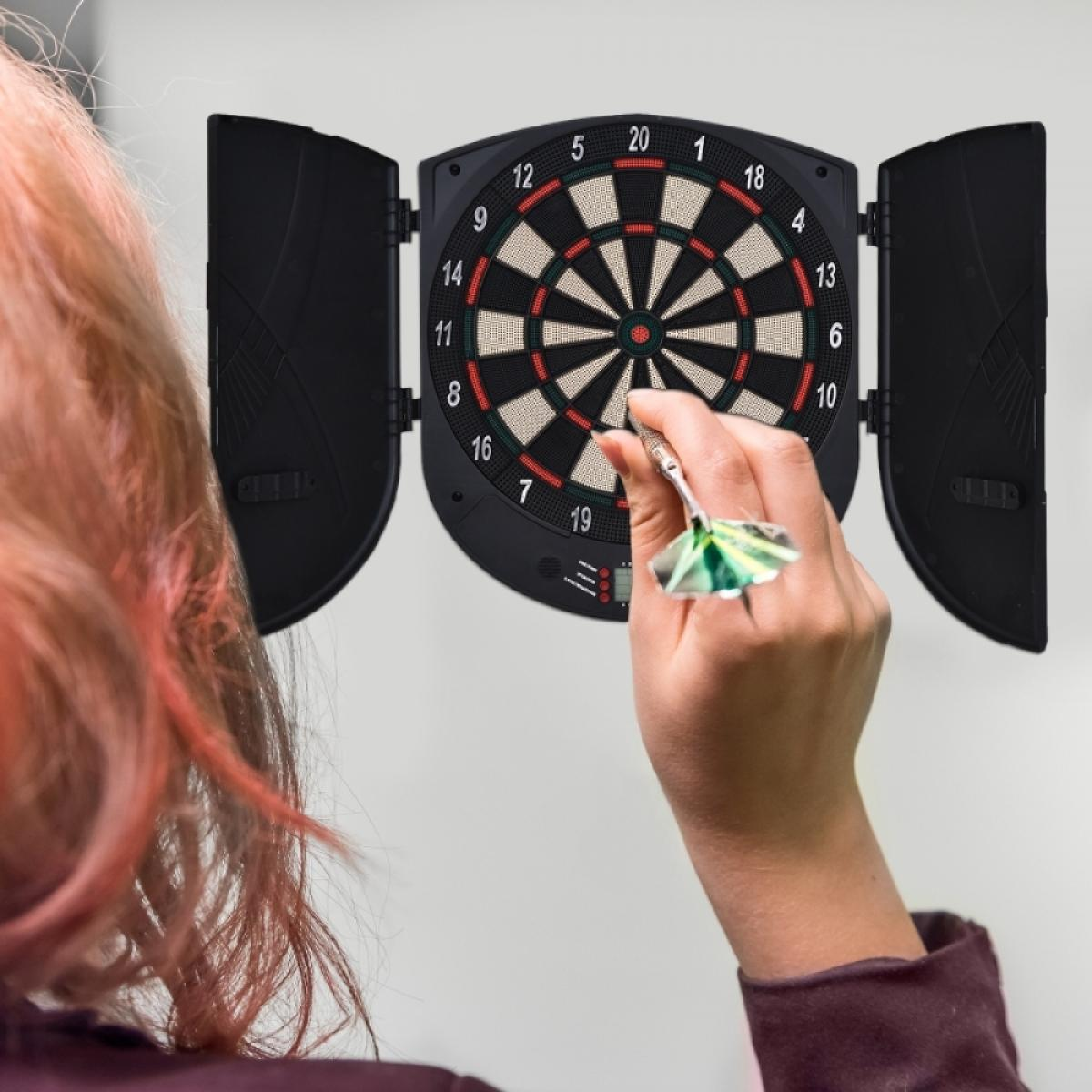 Eine Hand wirft einen Dartpfeil auf eine Dartscheibe mit Zahlen.