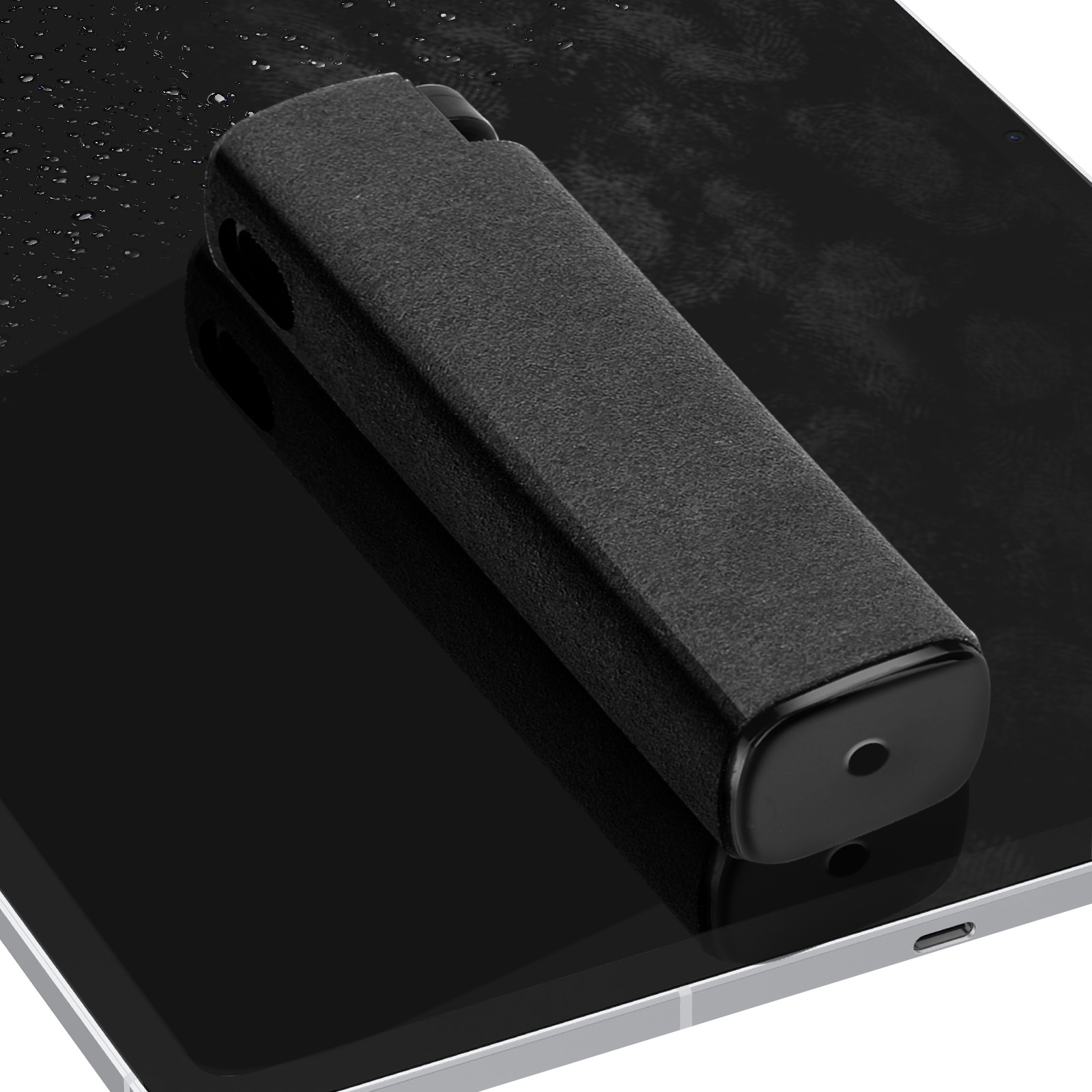Un attrezzo per la pulizia rettangolare nero giace su un tablet nero.