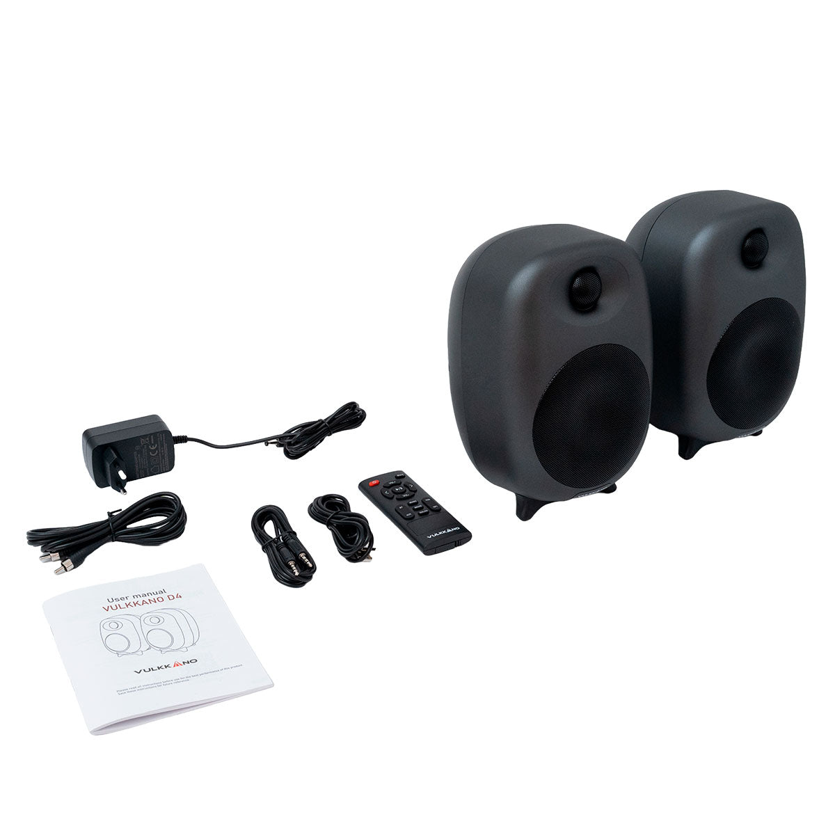 Dos altavoces negros, adaptador de corriente, mando, cables y manual en blanco.
