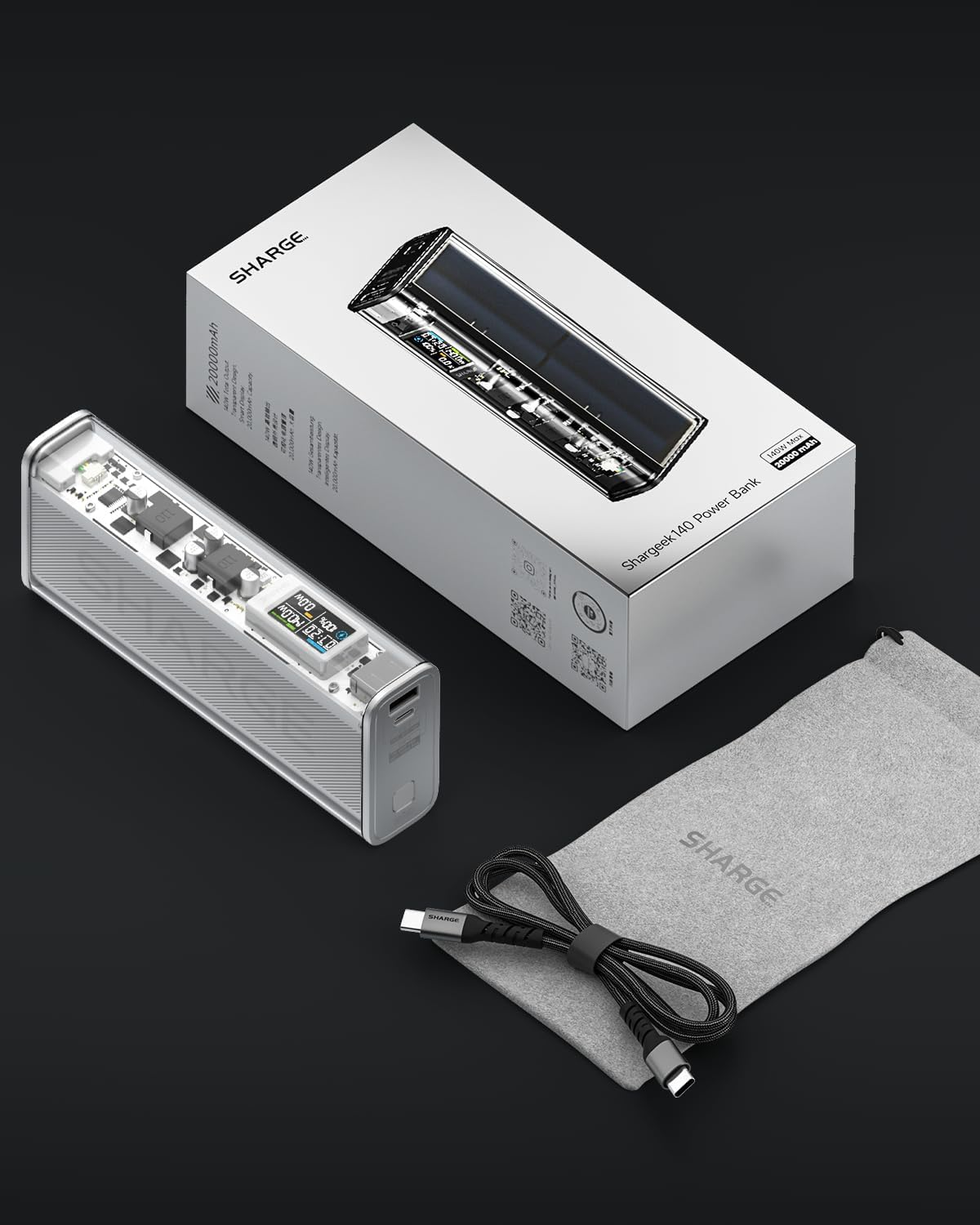 Batterie externe transparente, câble de chargement, pochette et boîte sur fond sombre.
