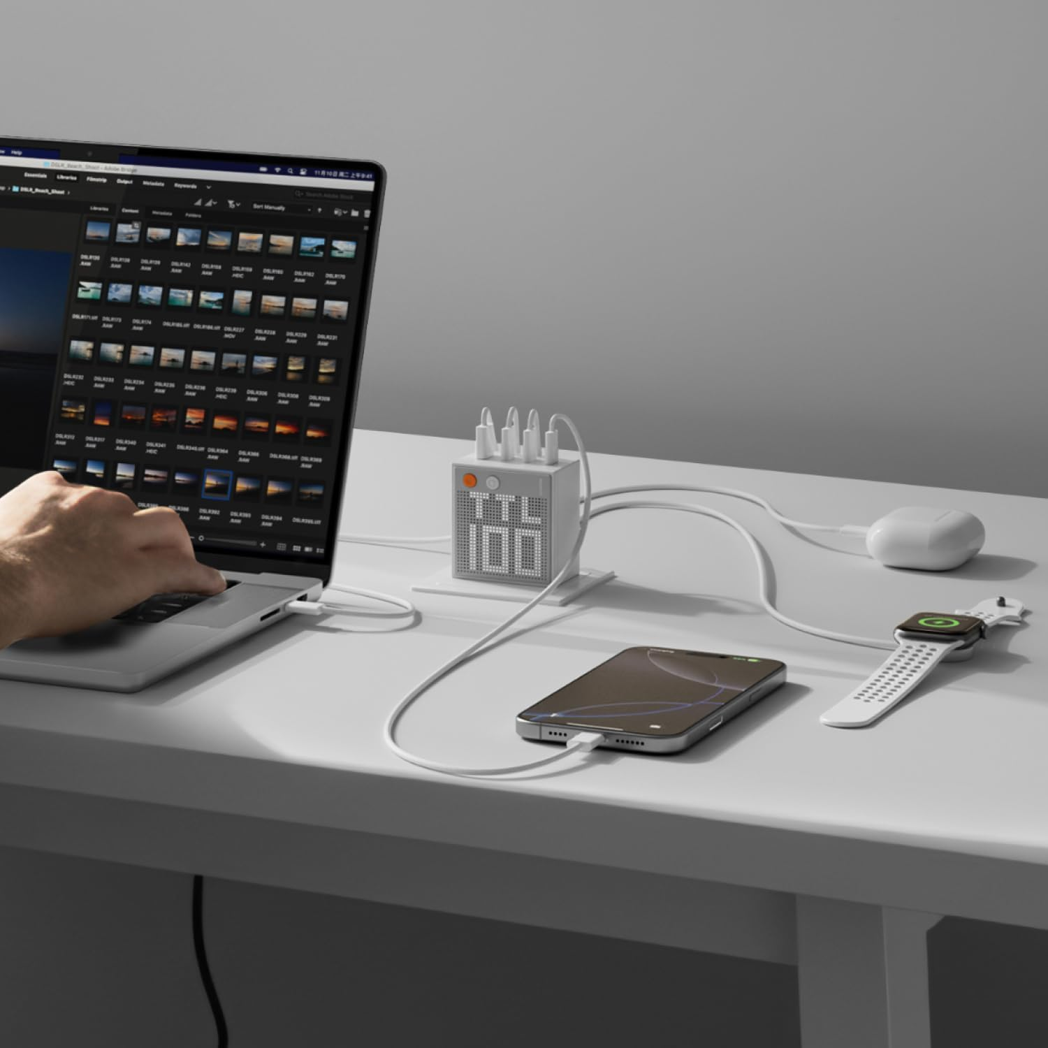 Un laptop, un telefono, uno smartwatch e auricolari si caricano su una scrivania.