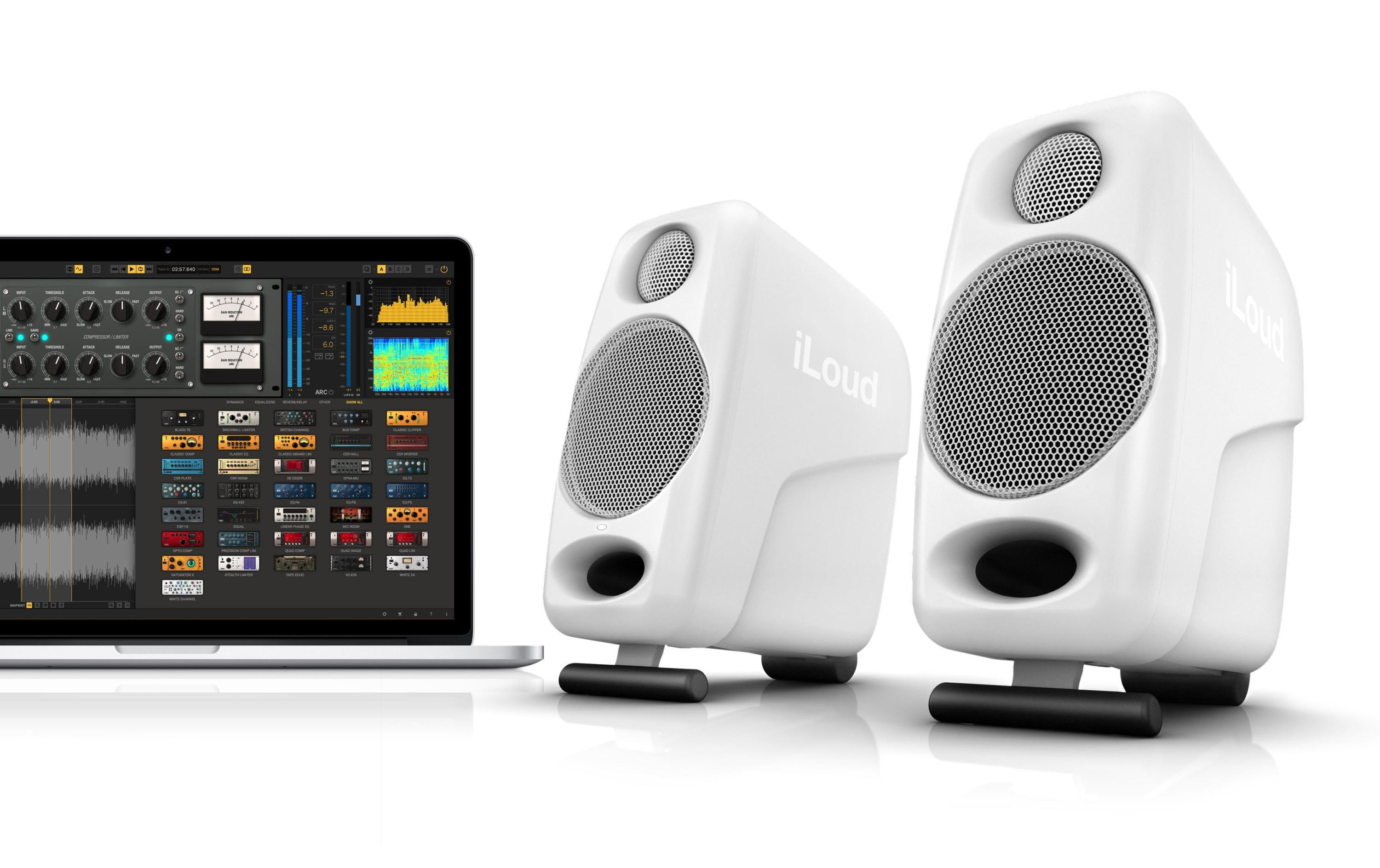 Due altoparlanti bianchi iLoud accanto a un laptop che mostra software audio.