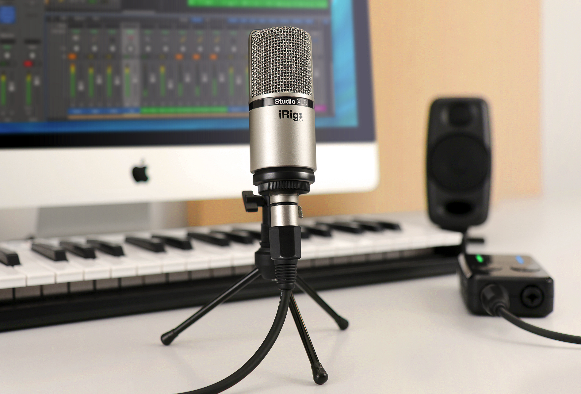 Mikrofon, Tastatur, Monitor mit Audio-Software und Lautsprecher auf einem Schreibtisch.