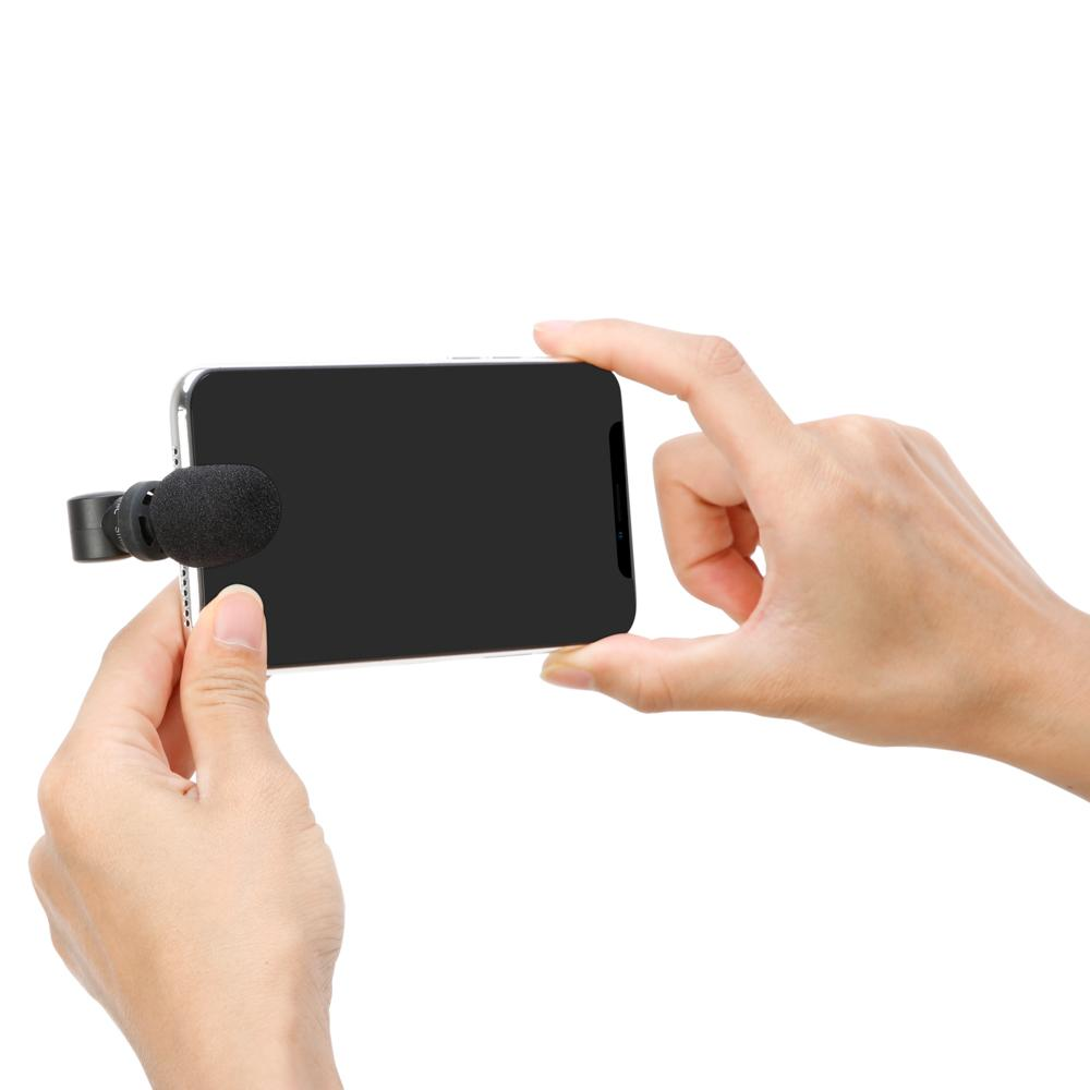 Manos sostienen un smartphone con micrófono, blanco.
