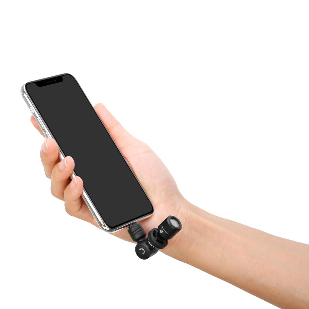 Mano sujetando smartphone con dos micrófonos pequeños en la muñeca.