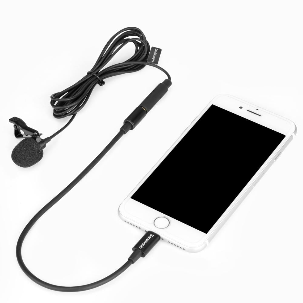 Micrófono lavalier con cable conectado a un smartphone blanco sobre fondo blanco.