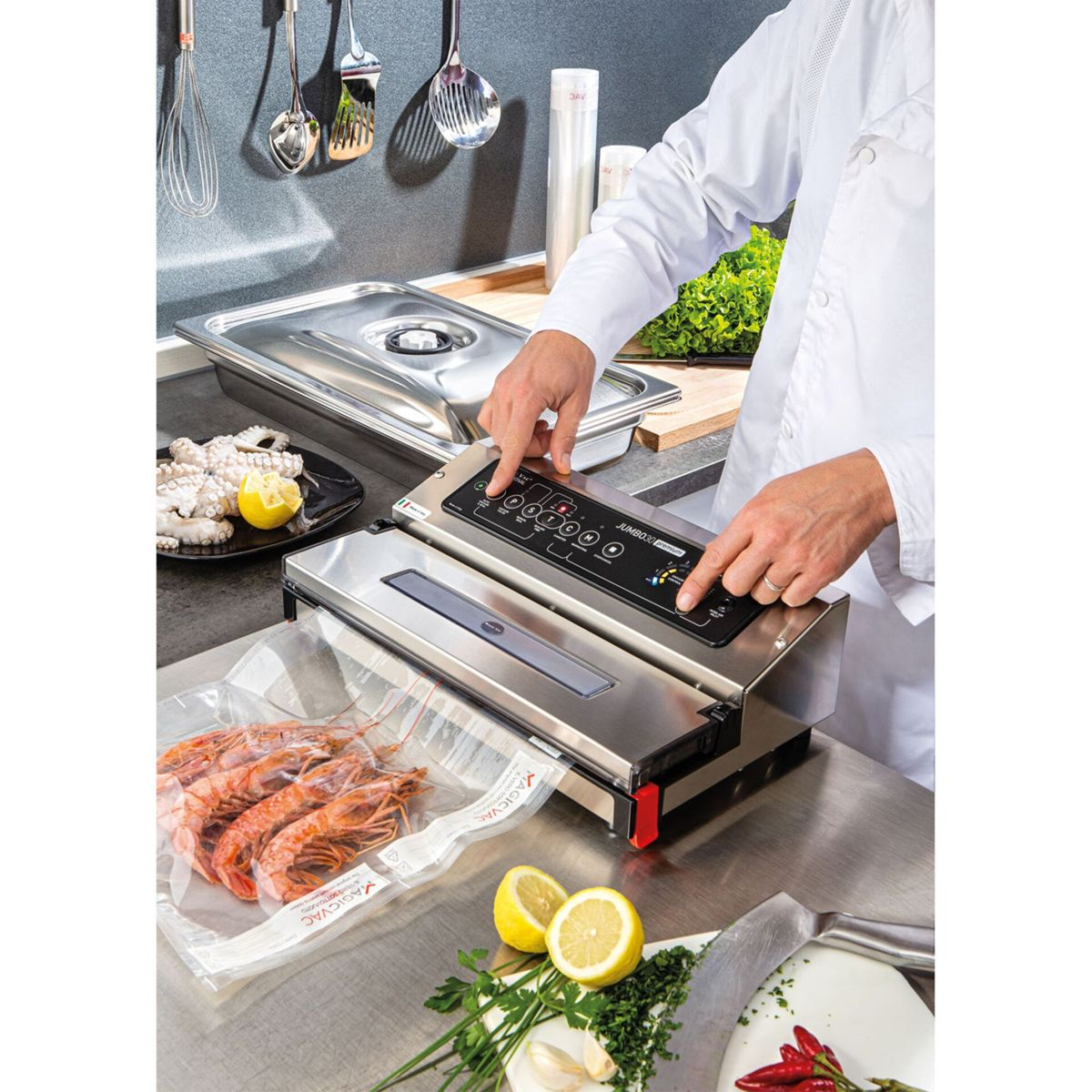 Kucharz pakuje próżniowo krewetki maszyną, z ośmiornicą i cytryną w tle.