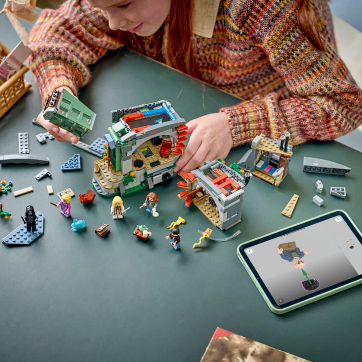 Dziecko buduje zestaw Lego z figurkami i instrukcją na tablecie.