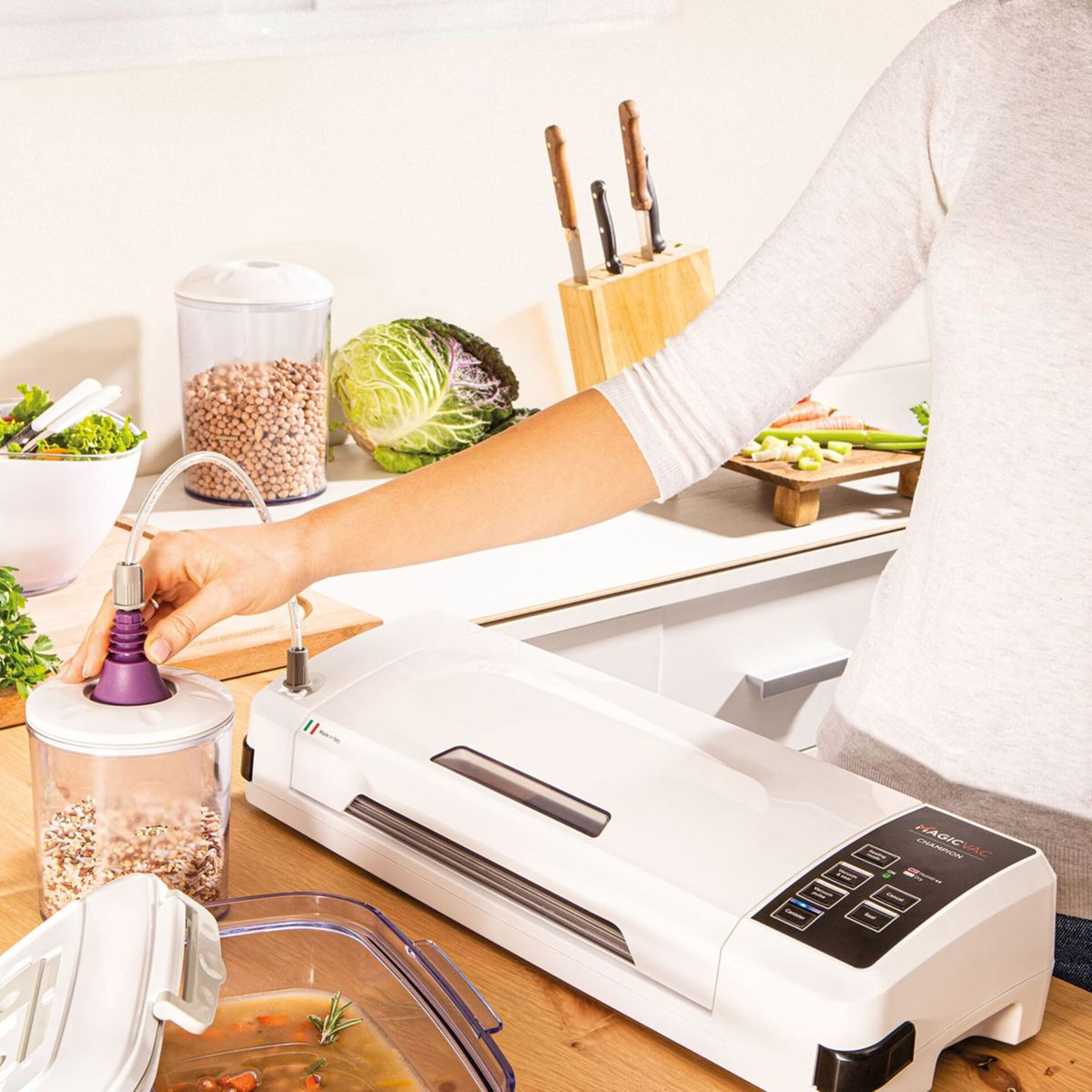 Osoba używająca pakowaczki próżniowej do konserwacji żywności w kuchni.