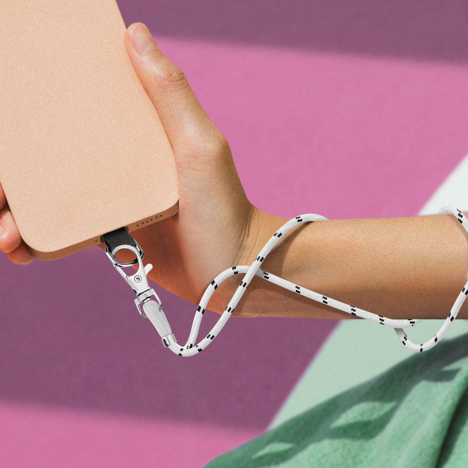 Una mano tiene un telefono chiaro attaccato a una corda bianca e nera.