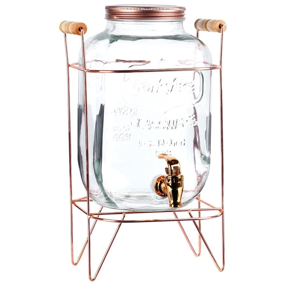 Un dispensador de vidrio transparente con grifo dorado y tapa de cobre.